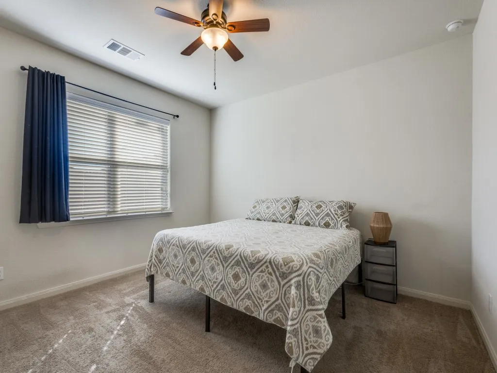 Carpeted bedroom with a ceiling fan and baseboards