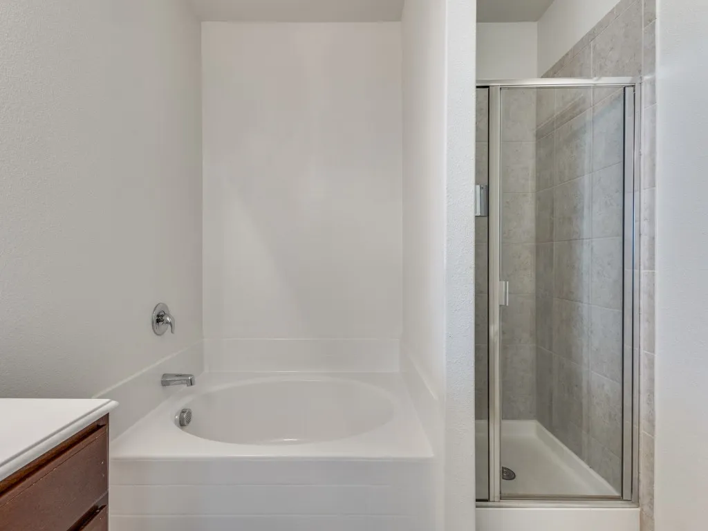 Full bath featuring a bath, a shower stall, vanity, and a textured wall