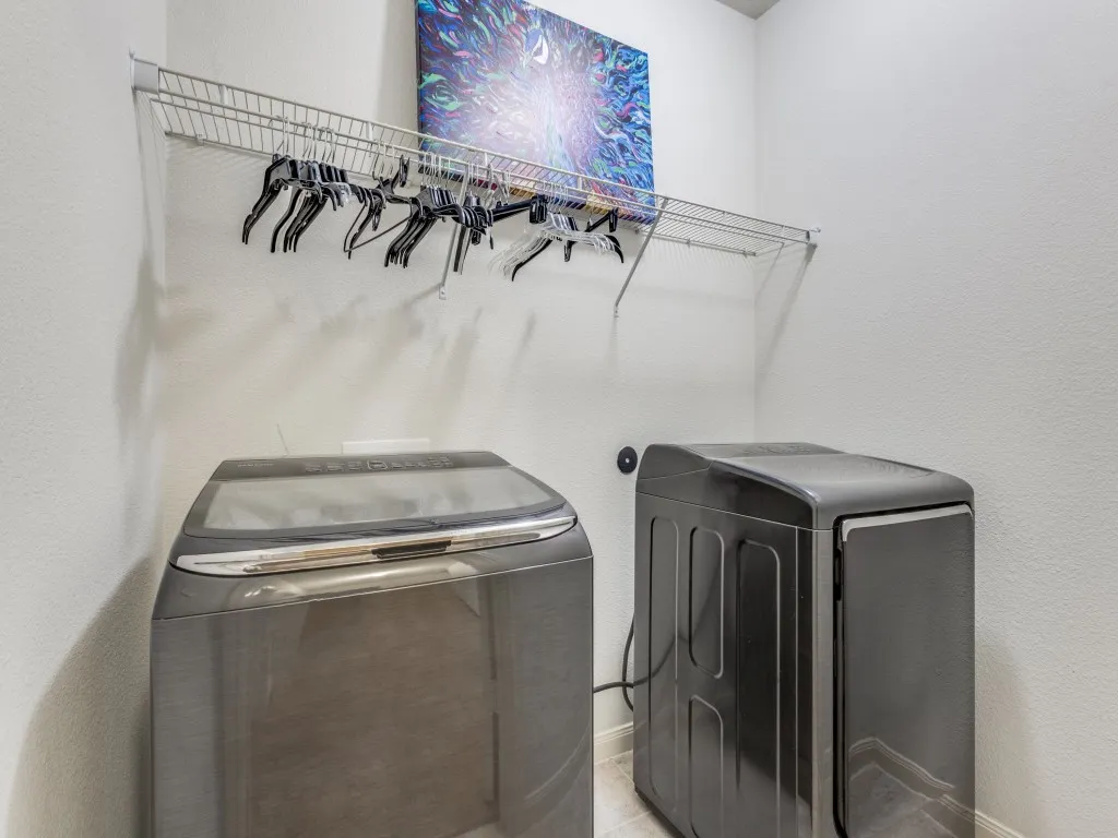 Laundry room with a textured wall and washing machine and clothes dryer