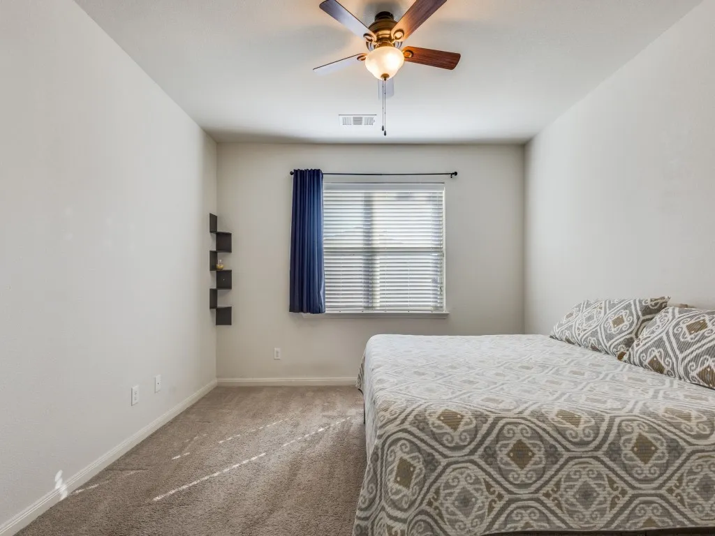 Carpeted bedroom with baseboards and a ceiling fan