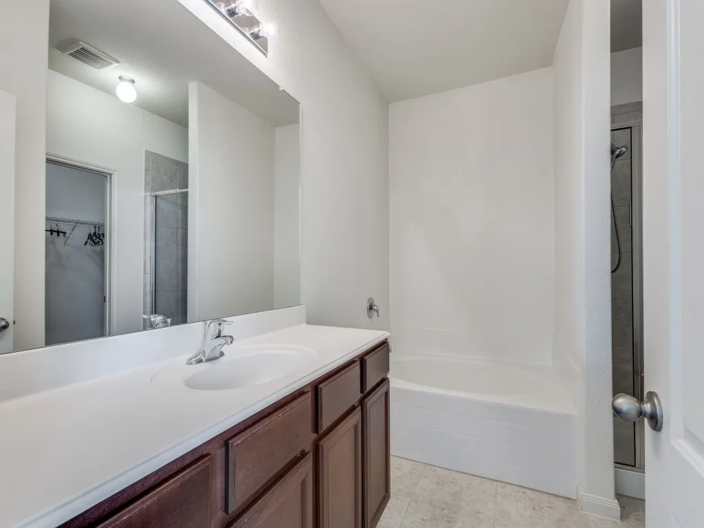 Bathroom featuring a walk in closet, a shower stall, a bath, and vanity