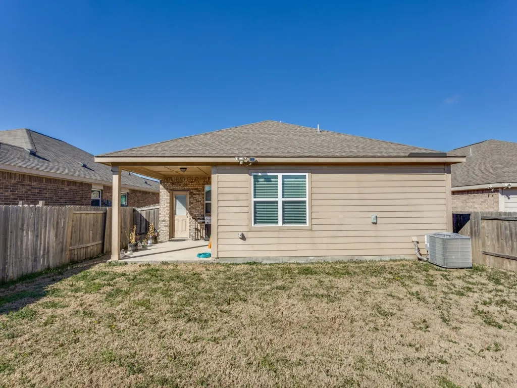 Rear view of property with a patio area, roof with shingles, a fenced backyard, and brick siding