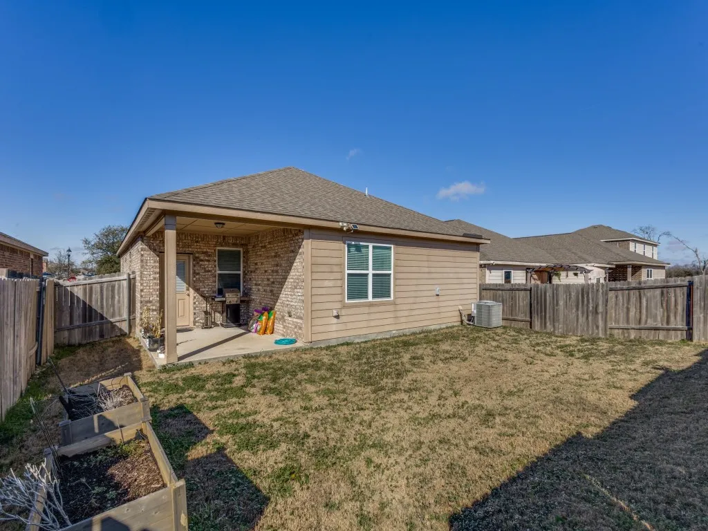 Rear view of house with a patio, brick siding, roof with shingles, and a fenced backyard