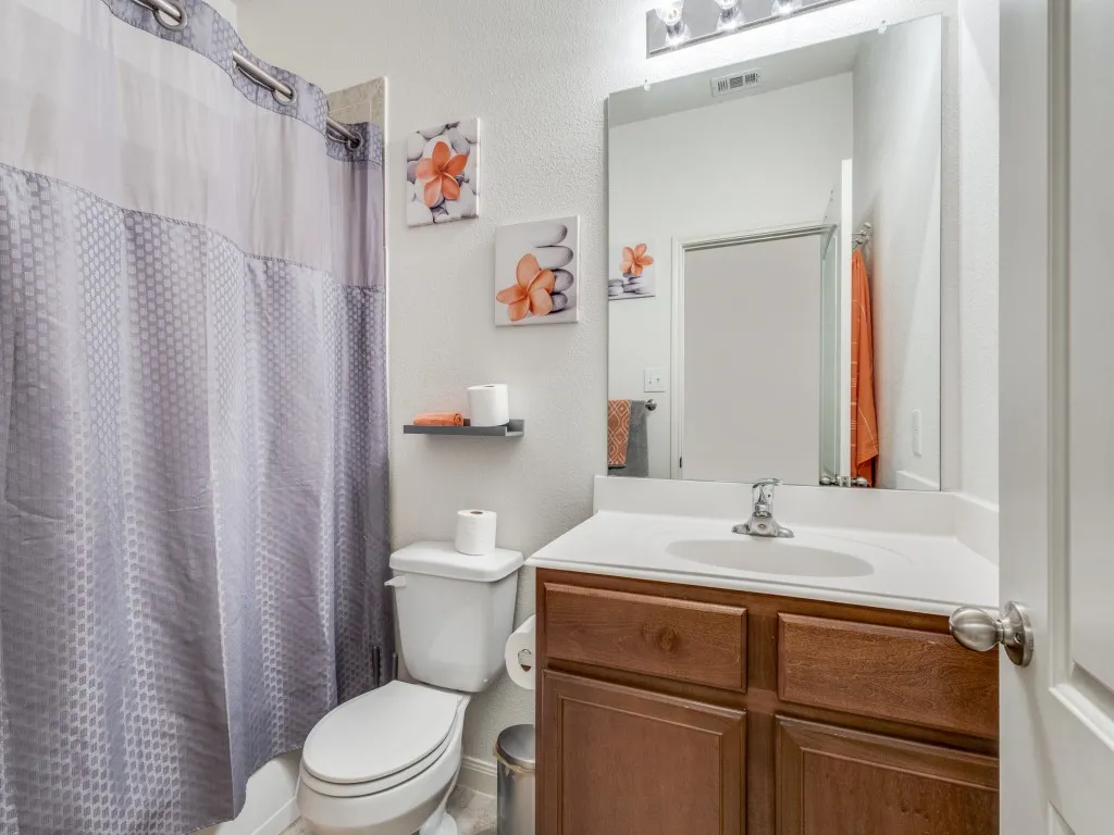 Bathroom featuring a textured wall, vanity, and shower / tub combo