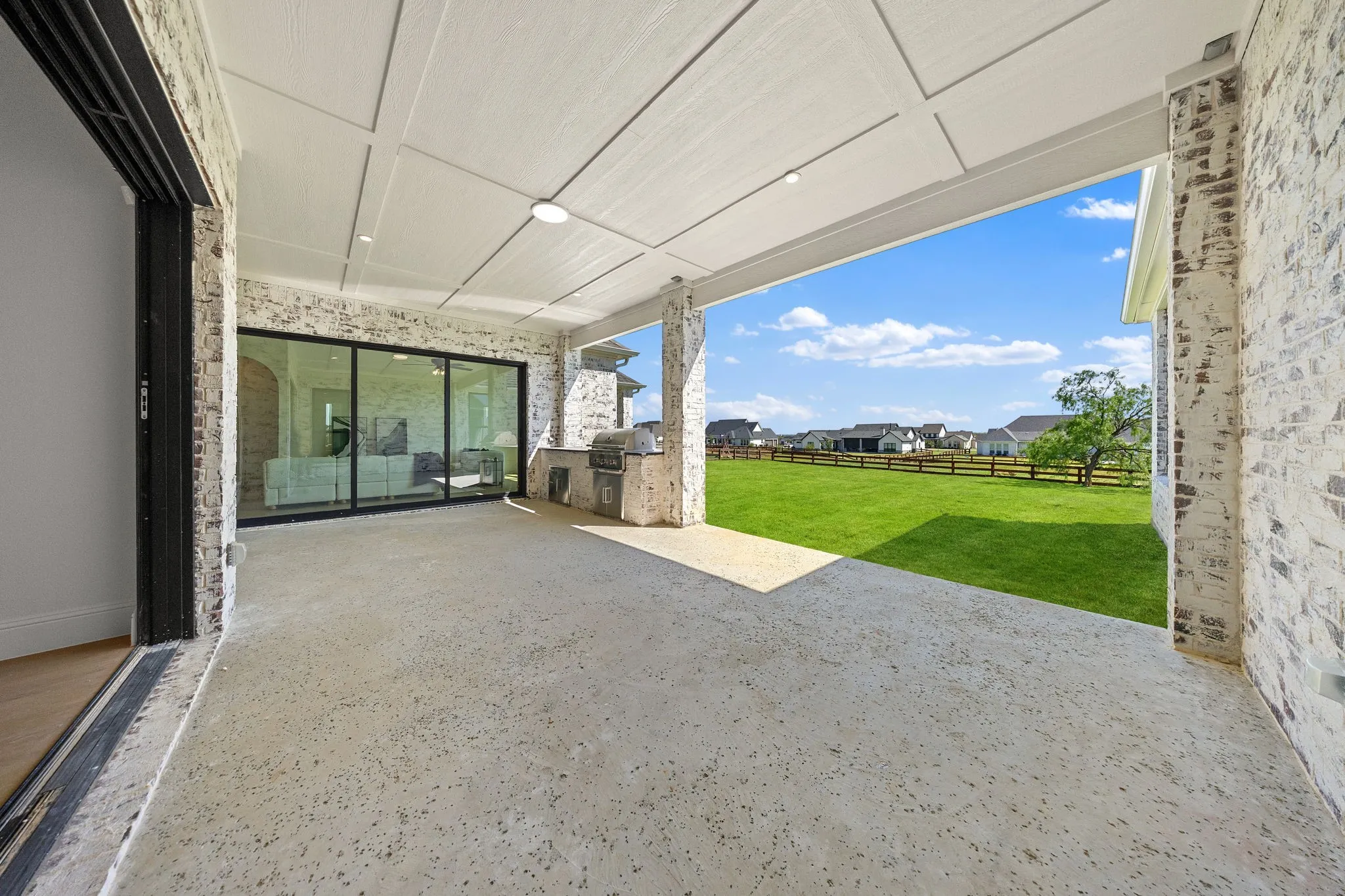 Covered patio with a board and batten ceiling, recessed lighting, and brick-clad columns