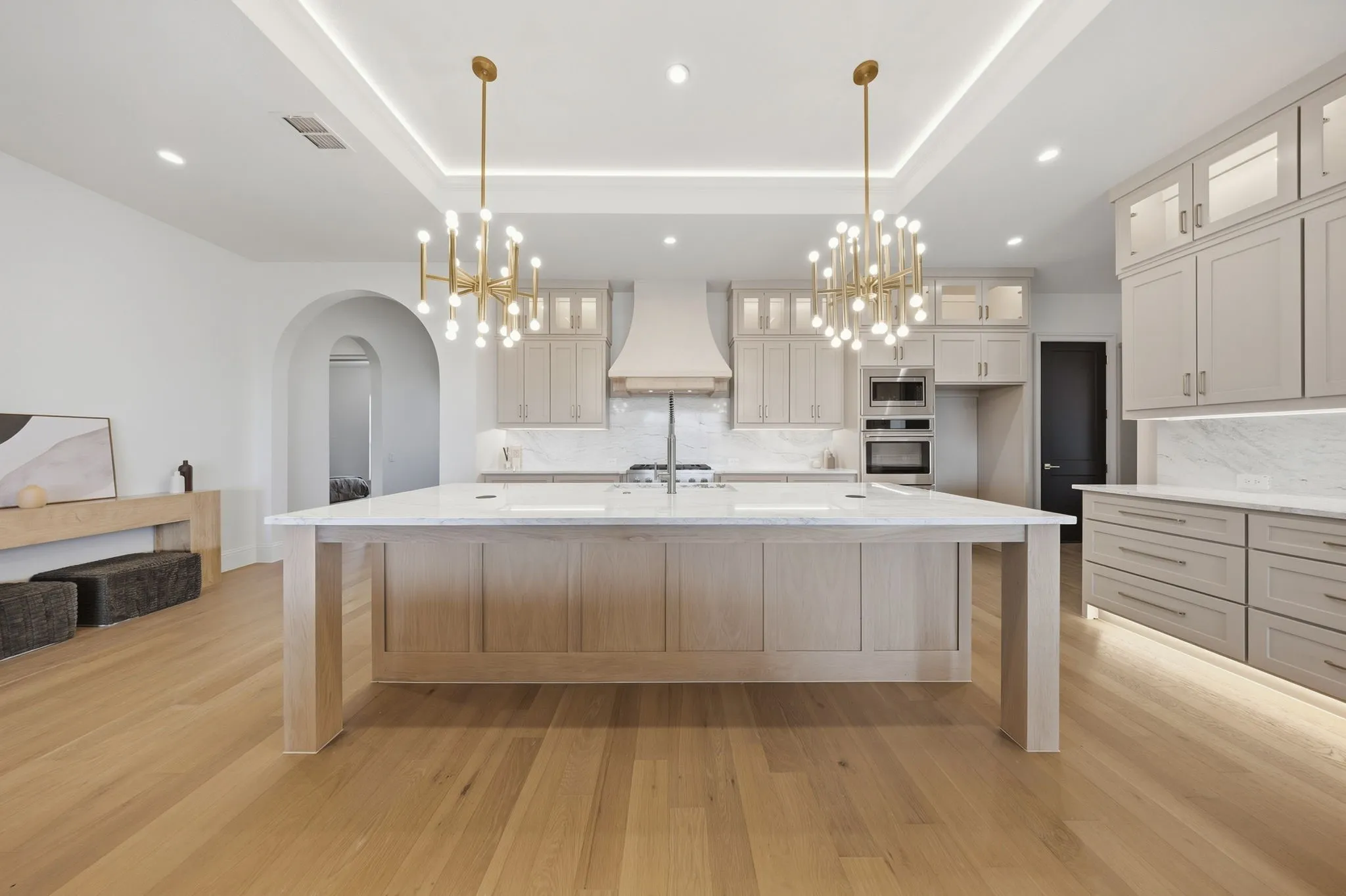Gourmet kitchen with a large island, wood-finish flooring, recessed lighting, and custom cabinetry