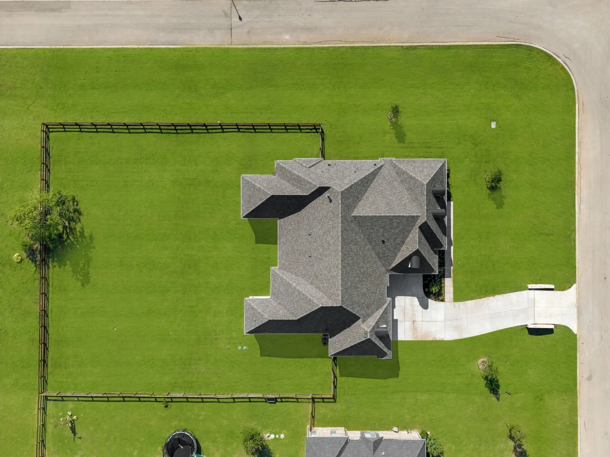 Expansive property featuring a multi-gabled roofline, concrete driveway, lush green lawn, and corner lot positioning