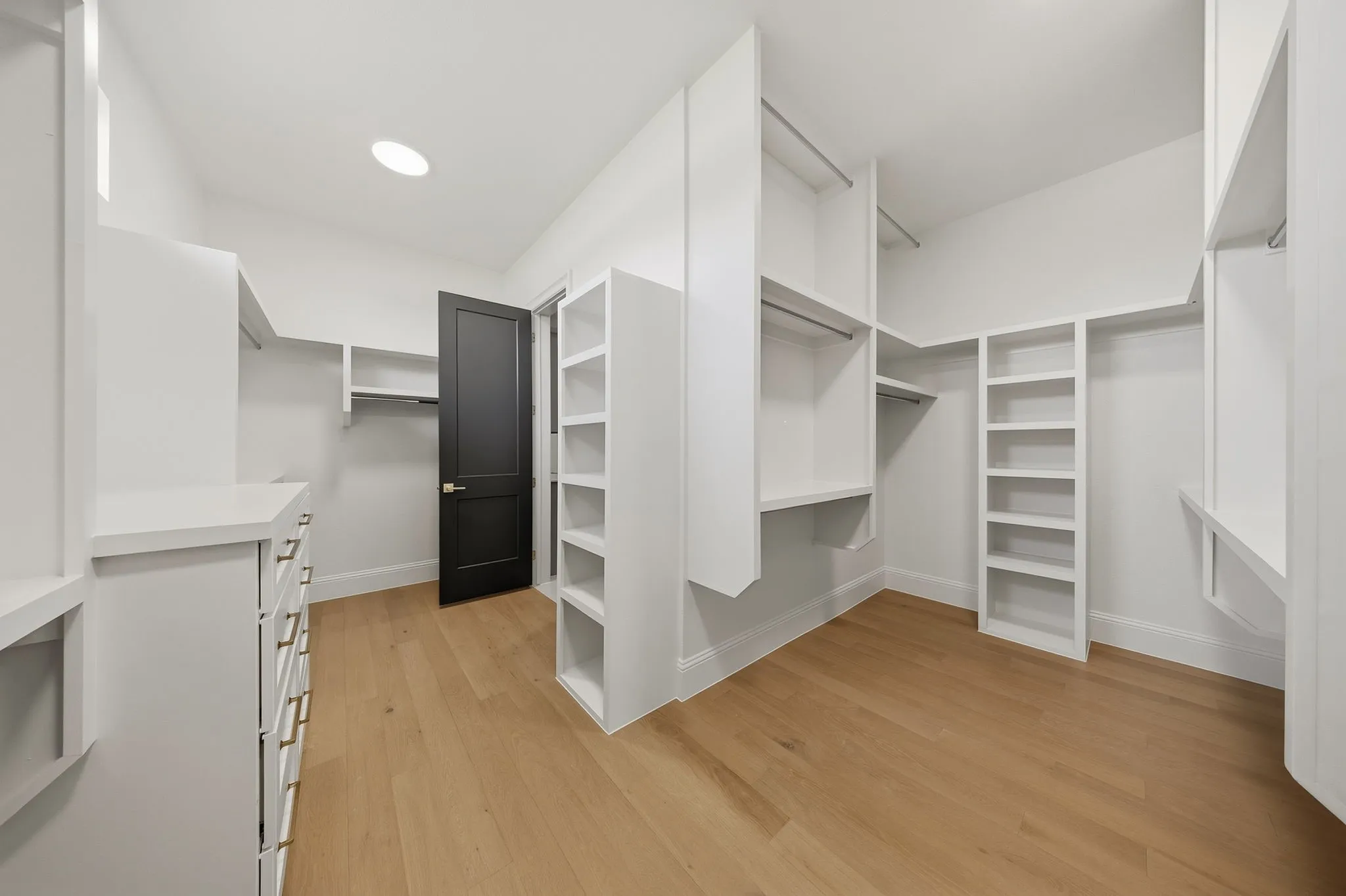 Walk-in closet with wood-finish flooring, recessed lighting, built-in shelving, hanging rods, and a built-in drawer unit