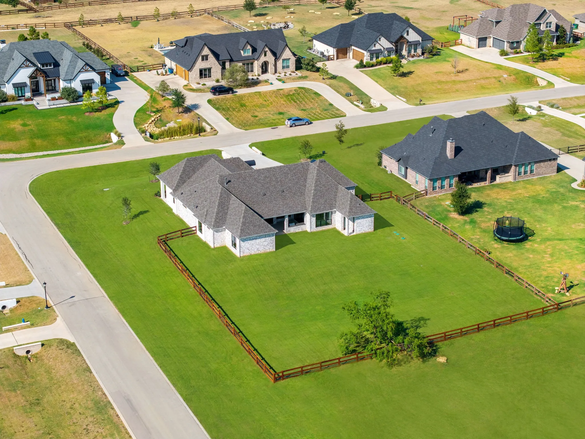 Expansive corner lot featuring a white brick exterior and a dark shingle roof