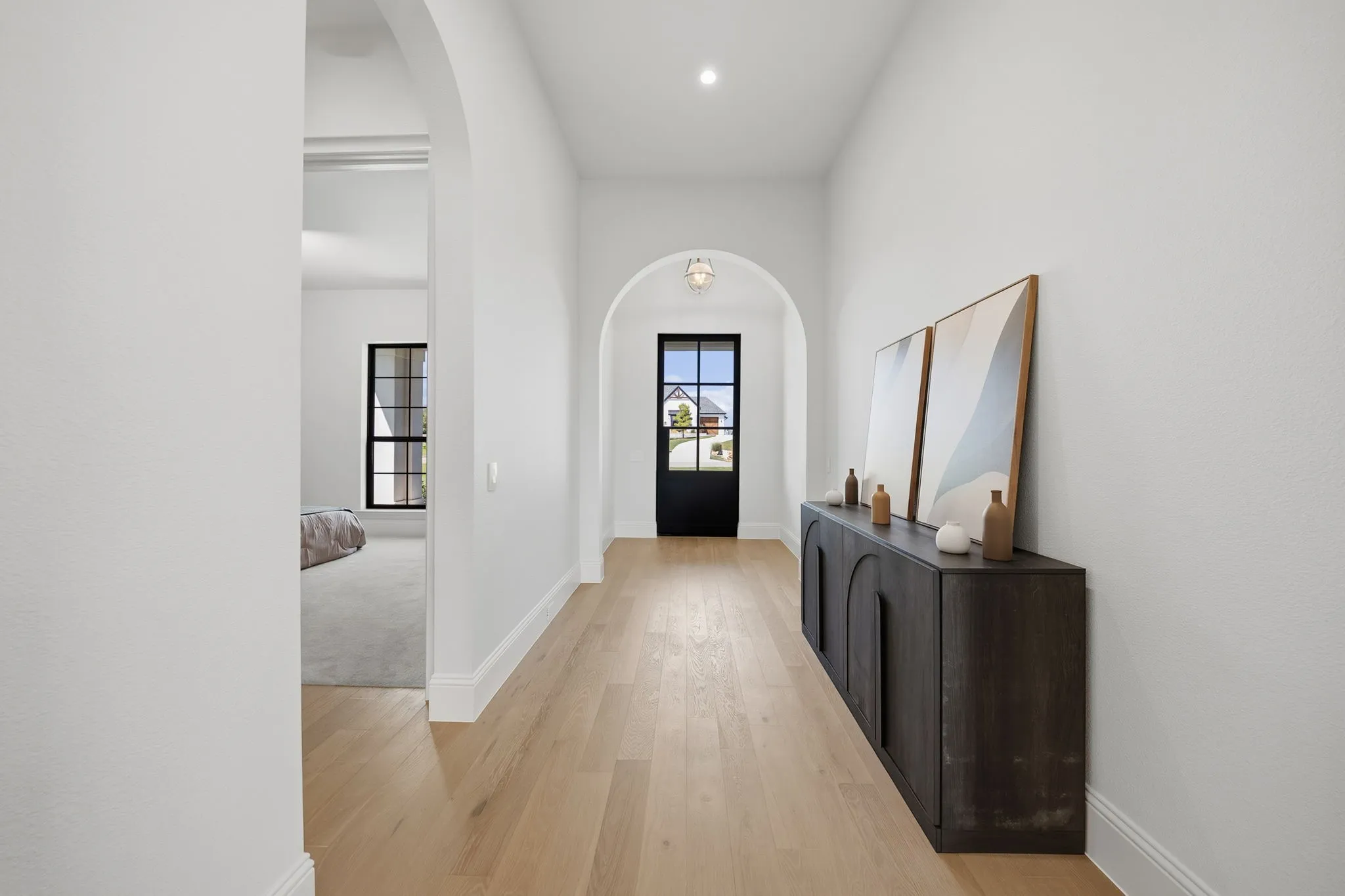 Archway entry, wood-finish flooring, white walls, recessed lighting, and a black-framed glass door