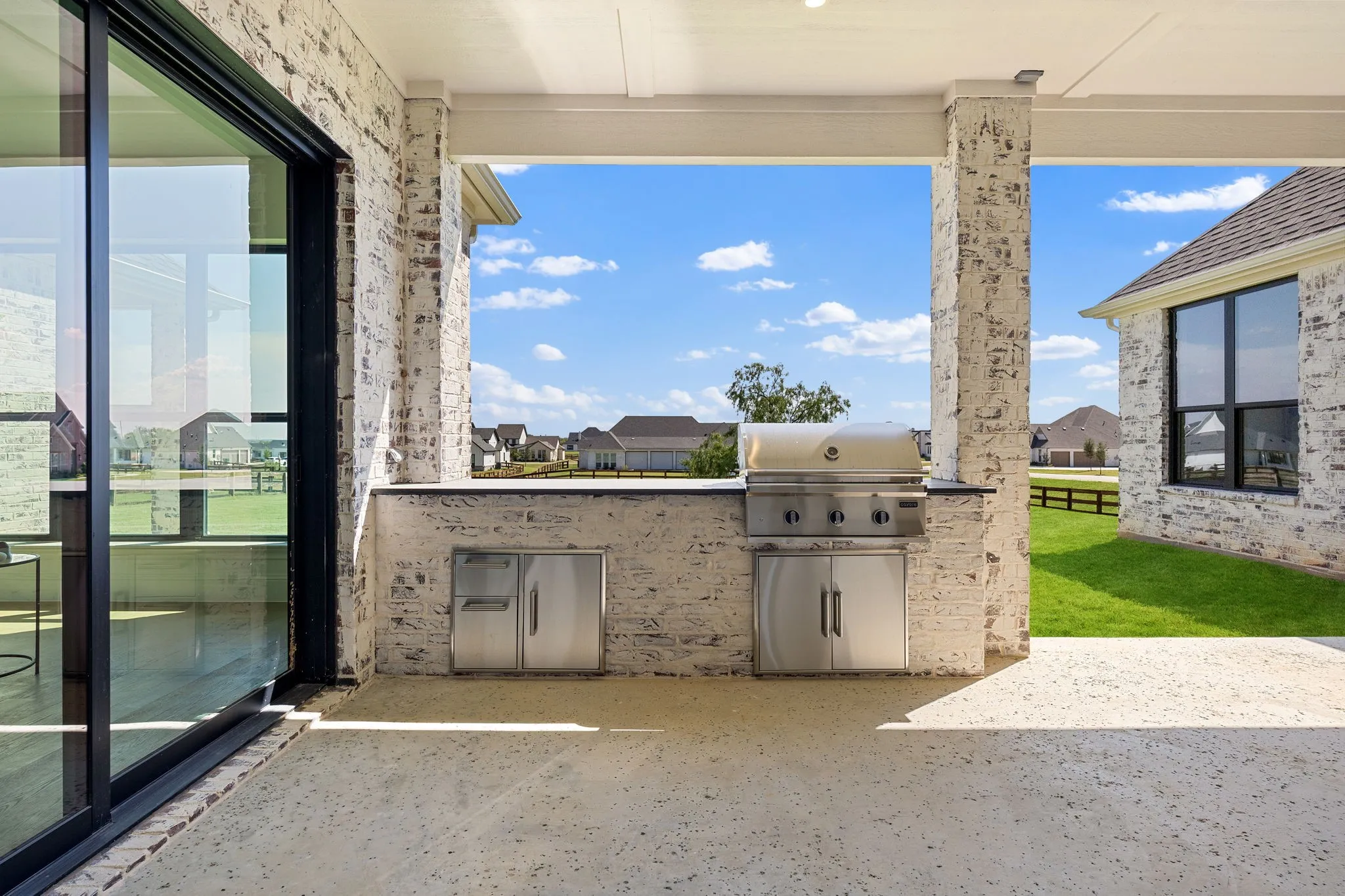 Covered patio with an outdoor kitchen, built-in grill, and sliding glass door access