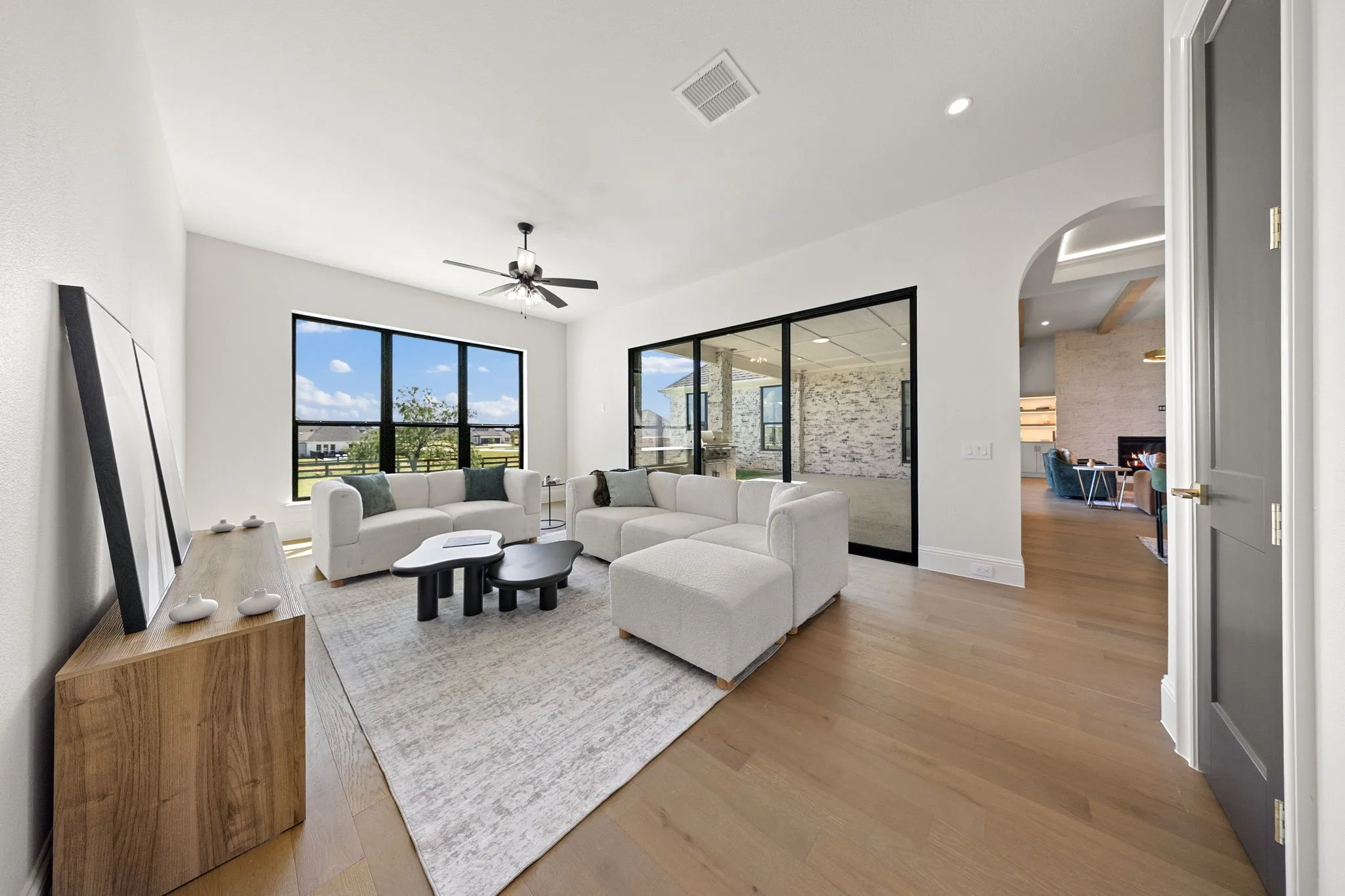 Light wood-finish flooring, a ceiling fan, and recessed lighting enhance the open living area