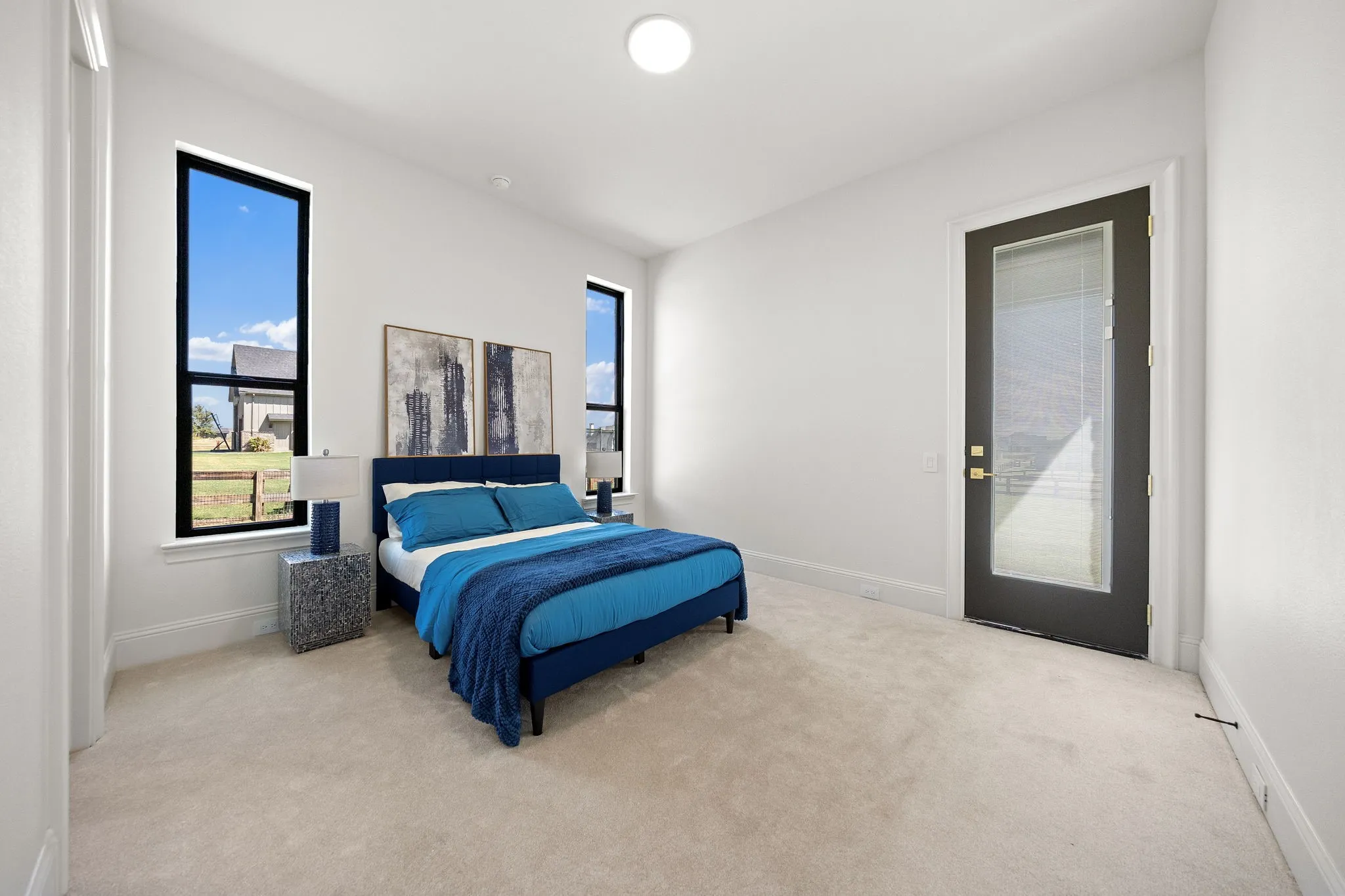 Plush carpeted flooring, multiple vertical windows with black frames, white painted walls, and a recessed ceiling light