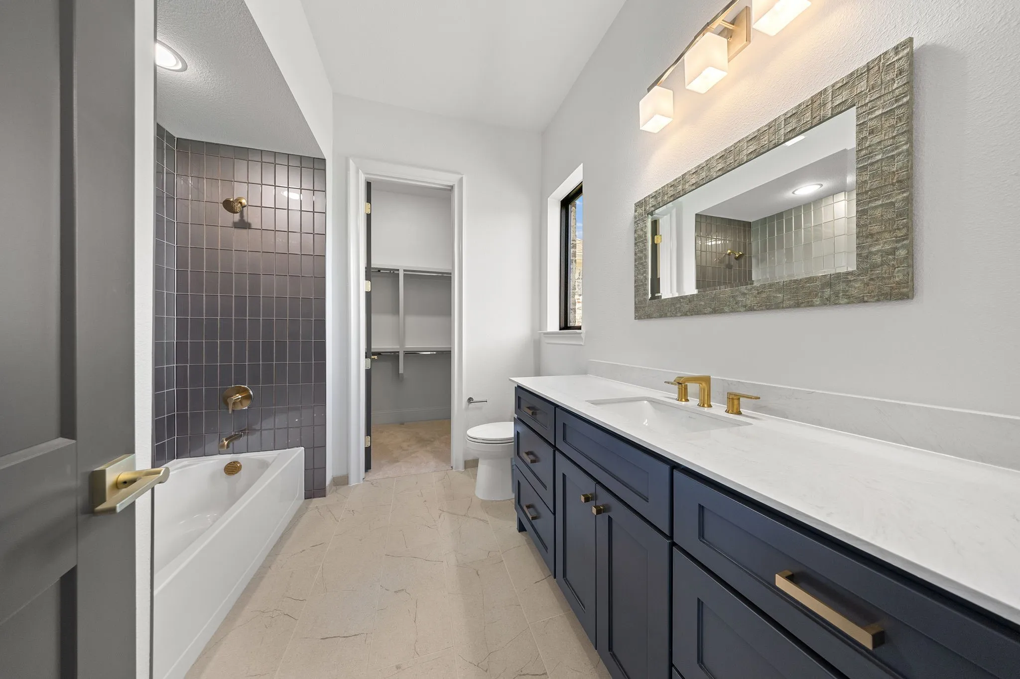 Dual basin vanity with quartz countertops, dark cabinetry, and gold-finish fixtures