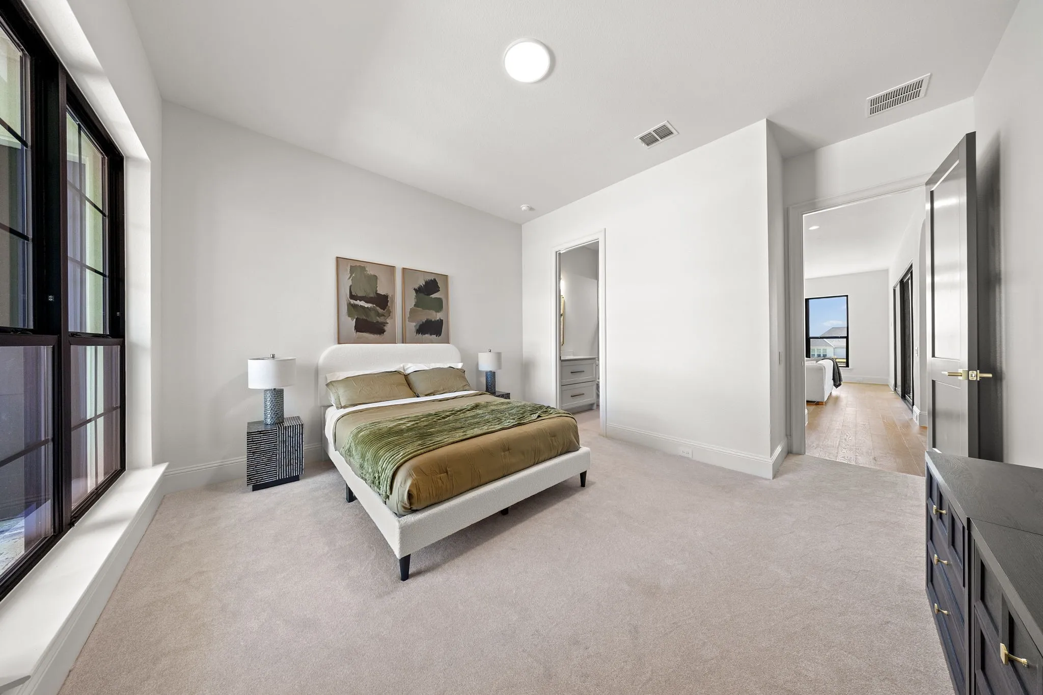 Plush carpet flooring, a vaulted ceiling, and a large multi-pane window with black framing