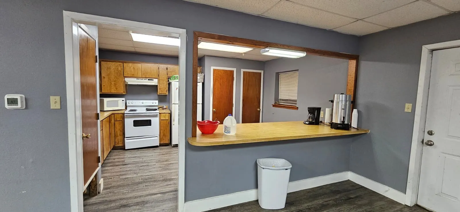 Kitchen with a paneled ceiling, wood finish cabinetry, white appliances, light countertops, and dark wood finished floors
