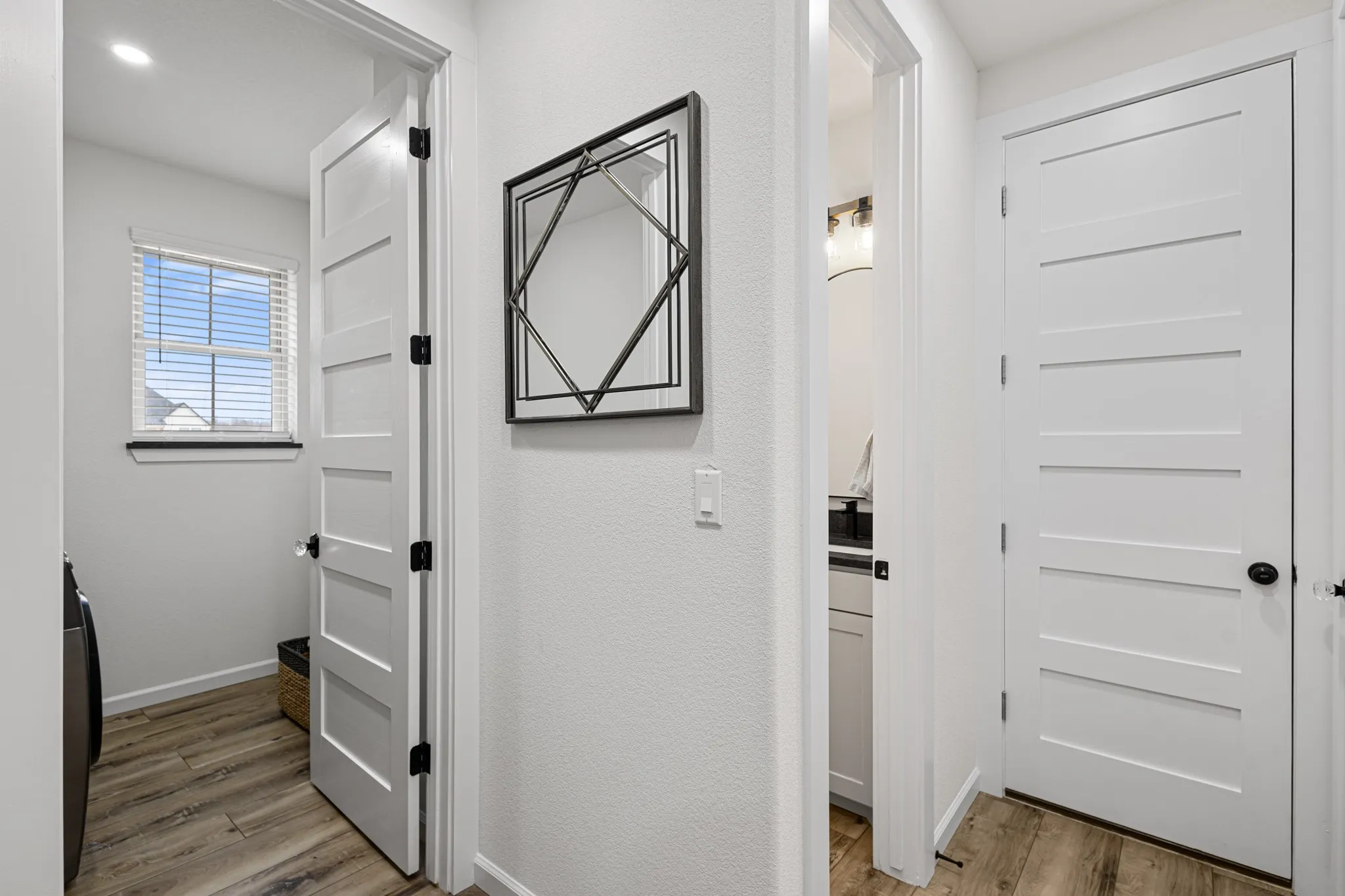 Hallway with laundry room to the left, access door to the garage, and partial view of the half bath