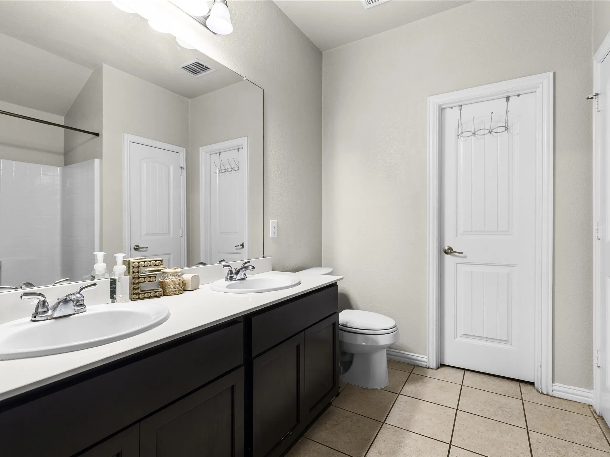 Bathroom with double vanity, light tile patterned floors, and a shower