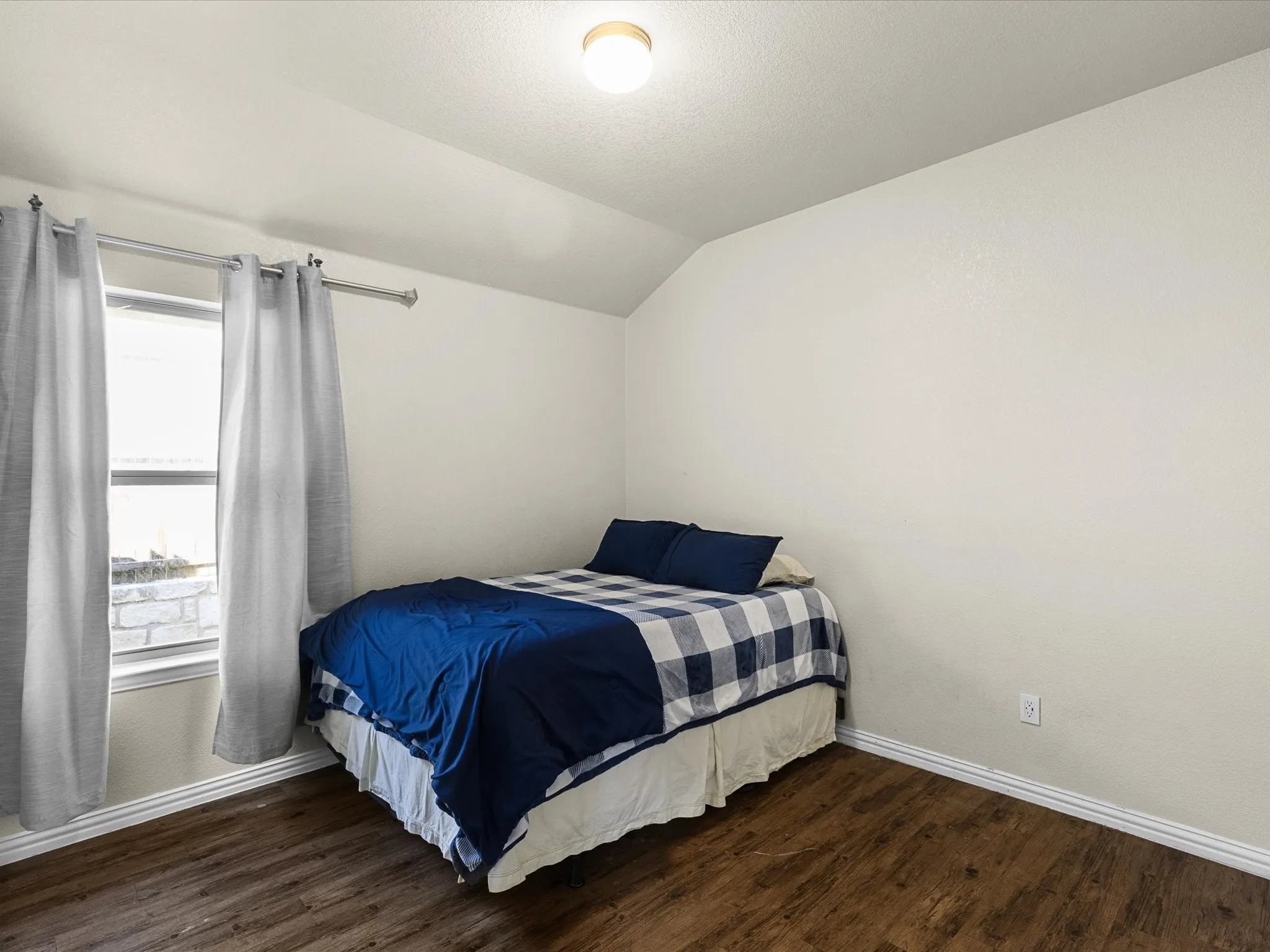 Bedroom with lofted ceiling and dark wood-style floors