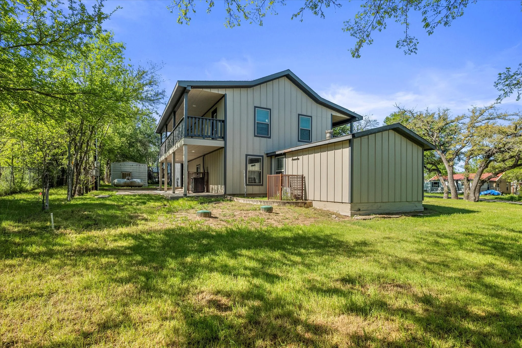 Back of house with board and batten siding, a lawn, and a patio area