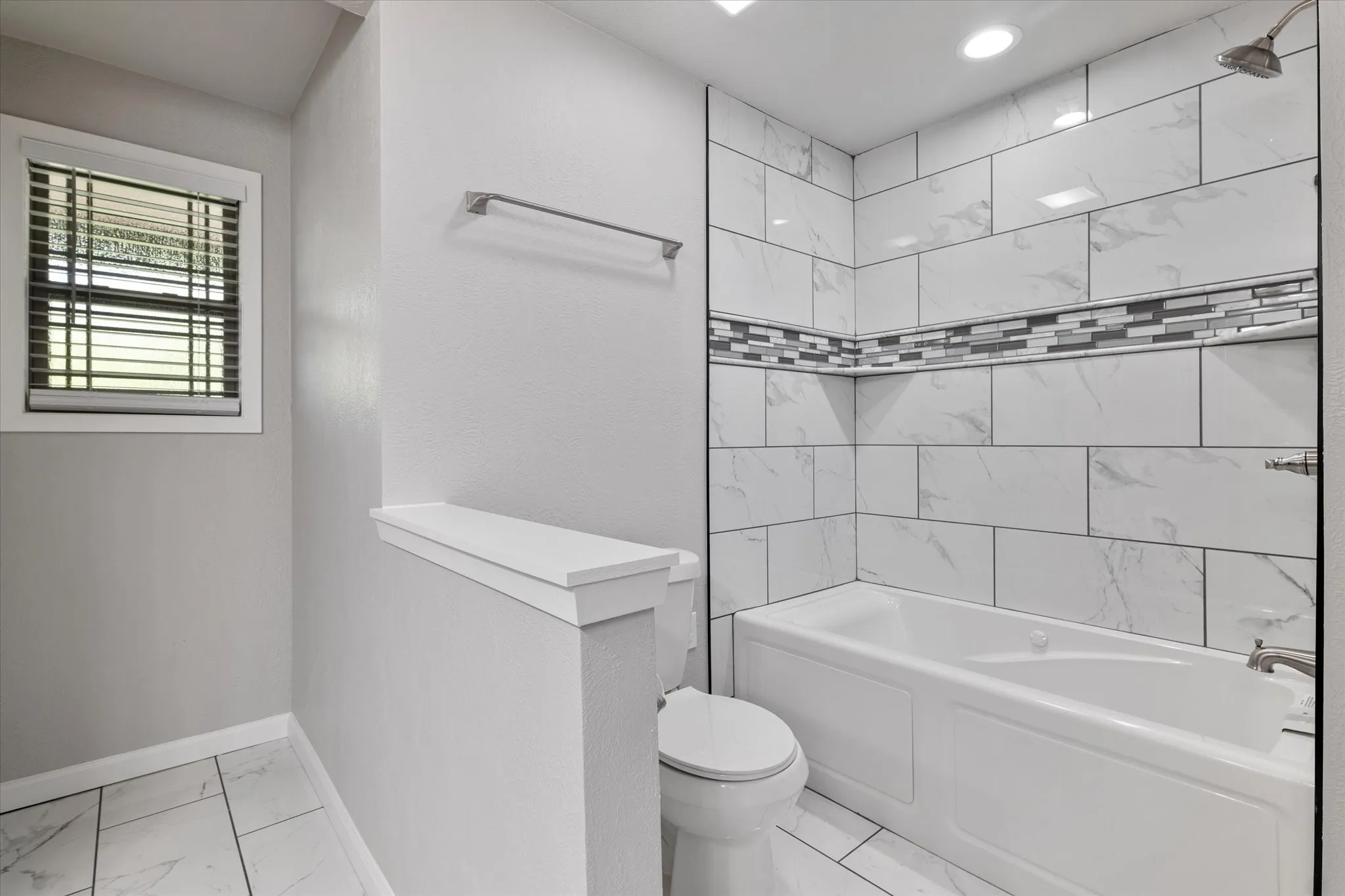 Full bathroom with shower / washtub combination and light marble finish floors