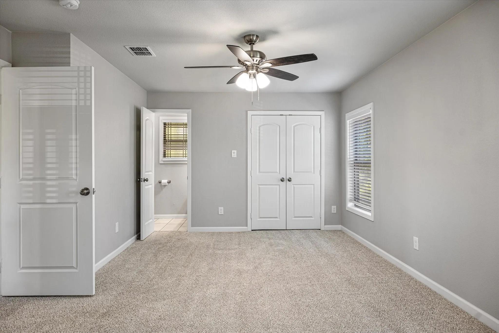 Unfurnished bedroom featuring light colored carpet, ceiling fan, and a closet