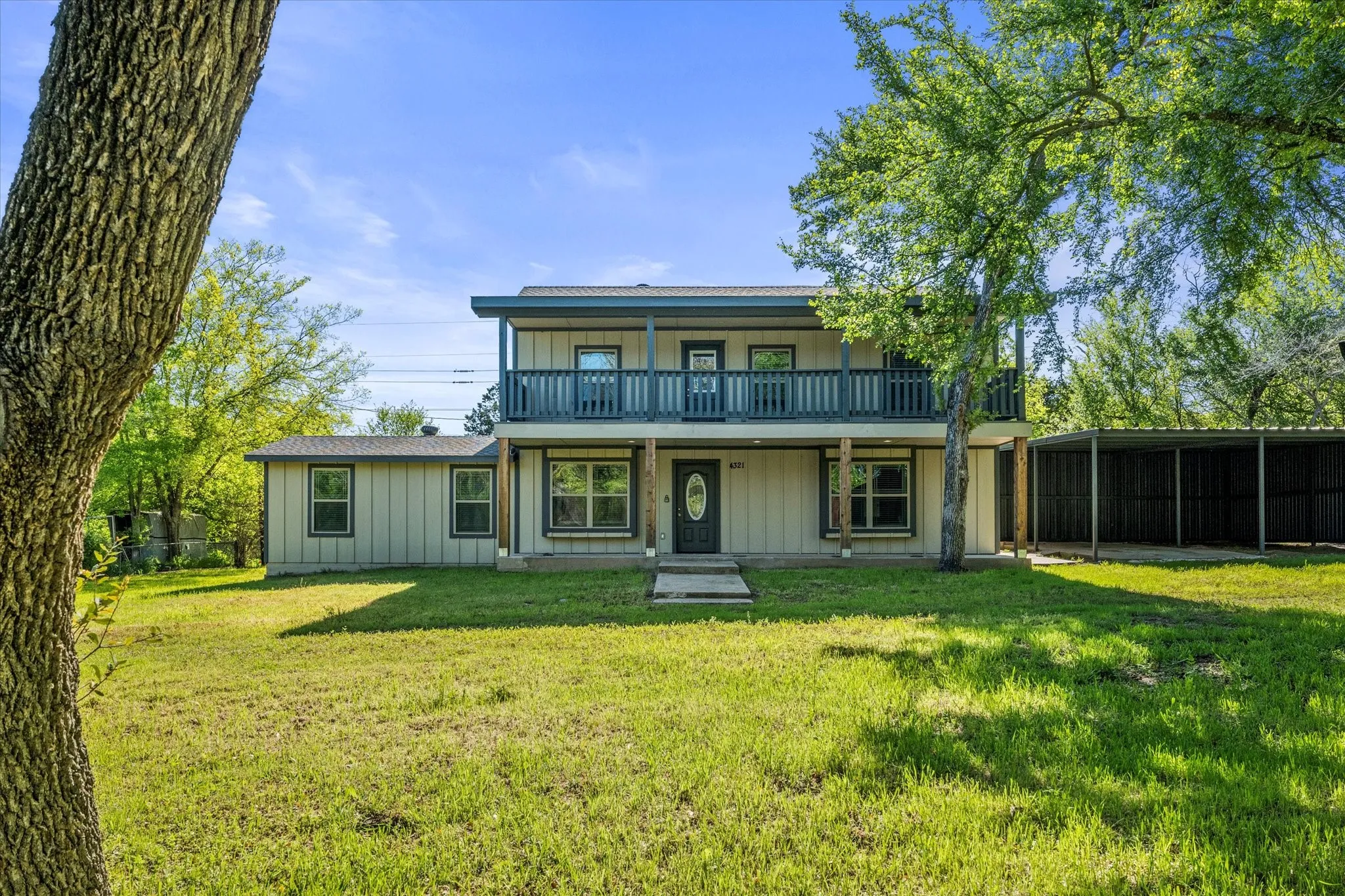 Back of property featuring board and batten siding, a balcony, and a carport