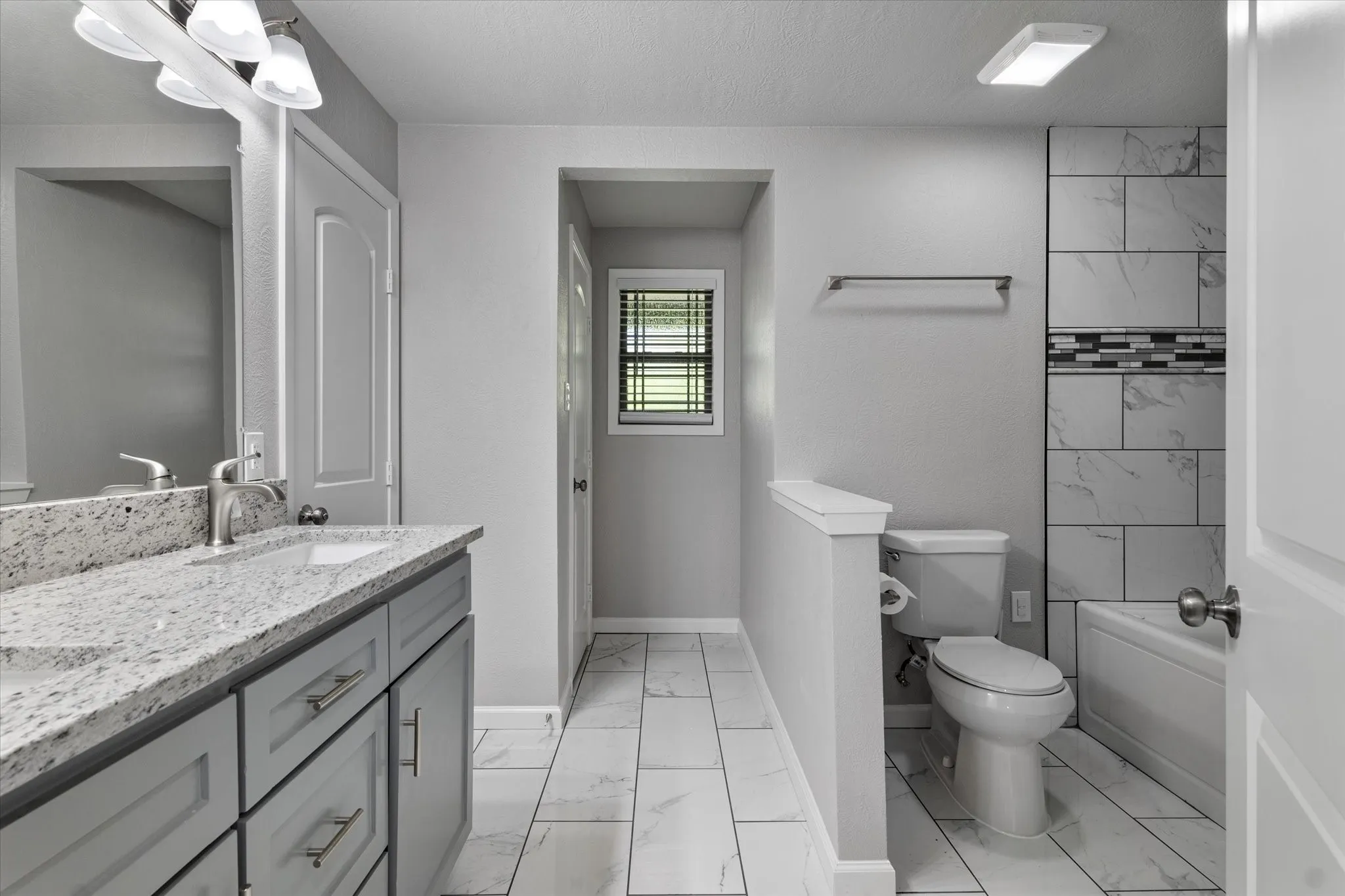 Full bath with double vanity, light marble finish flooring, and shower / bath combination