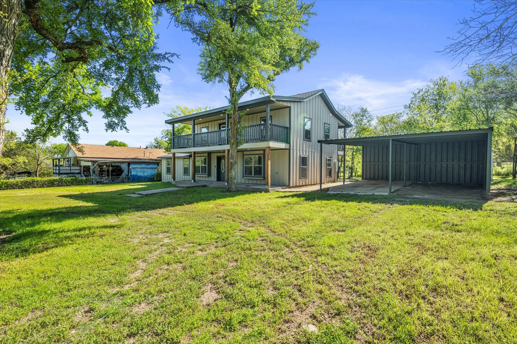 Back of property with a patio, a yard, board and batten siding, and a balcony