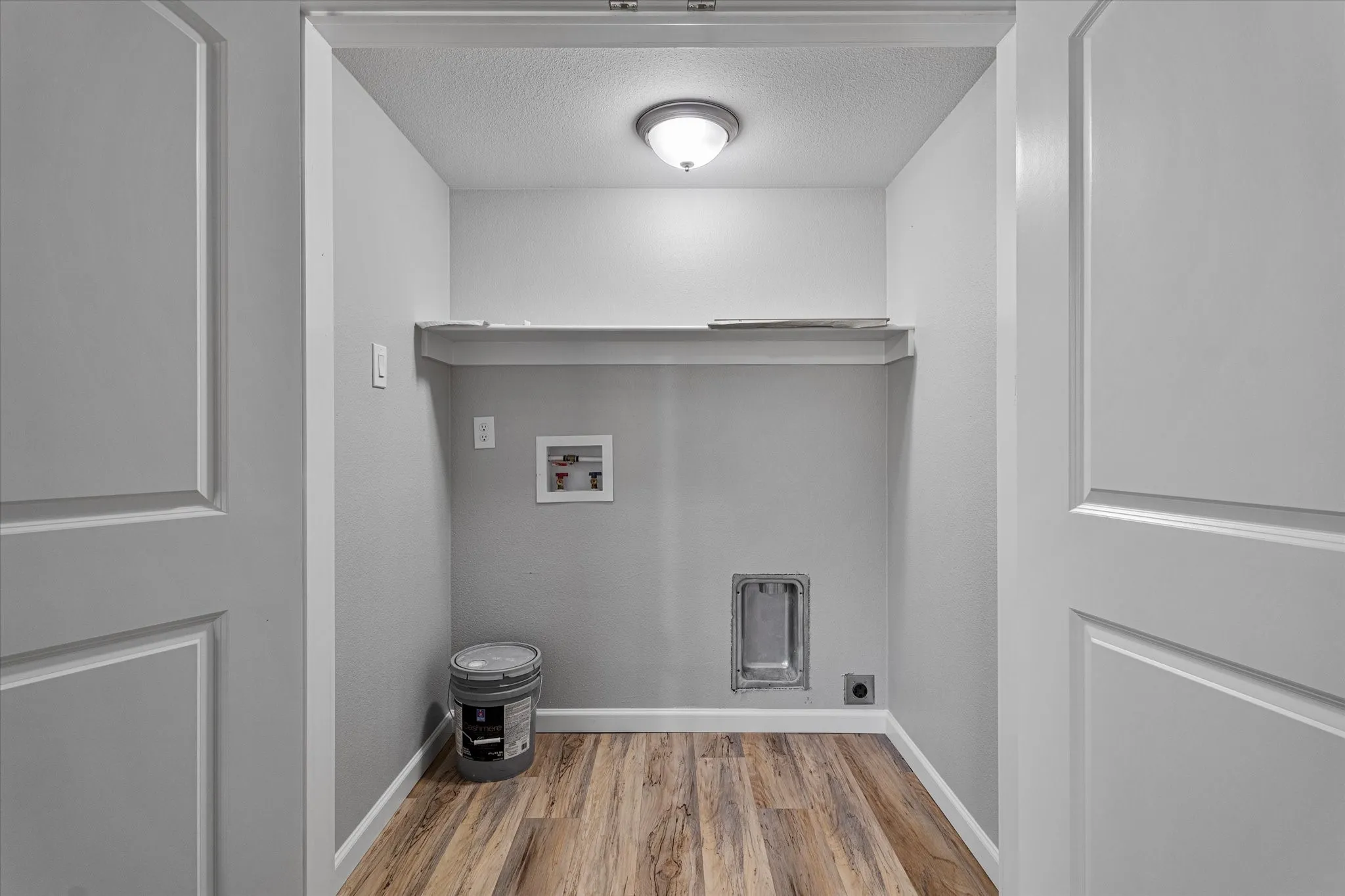 Laundry room featuring a textured ceiling, hookup for a washing machine, light wood-type flooring, and hookup for an electric dryer