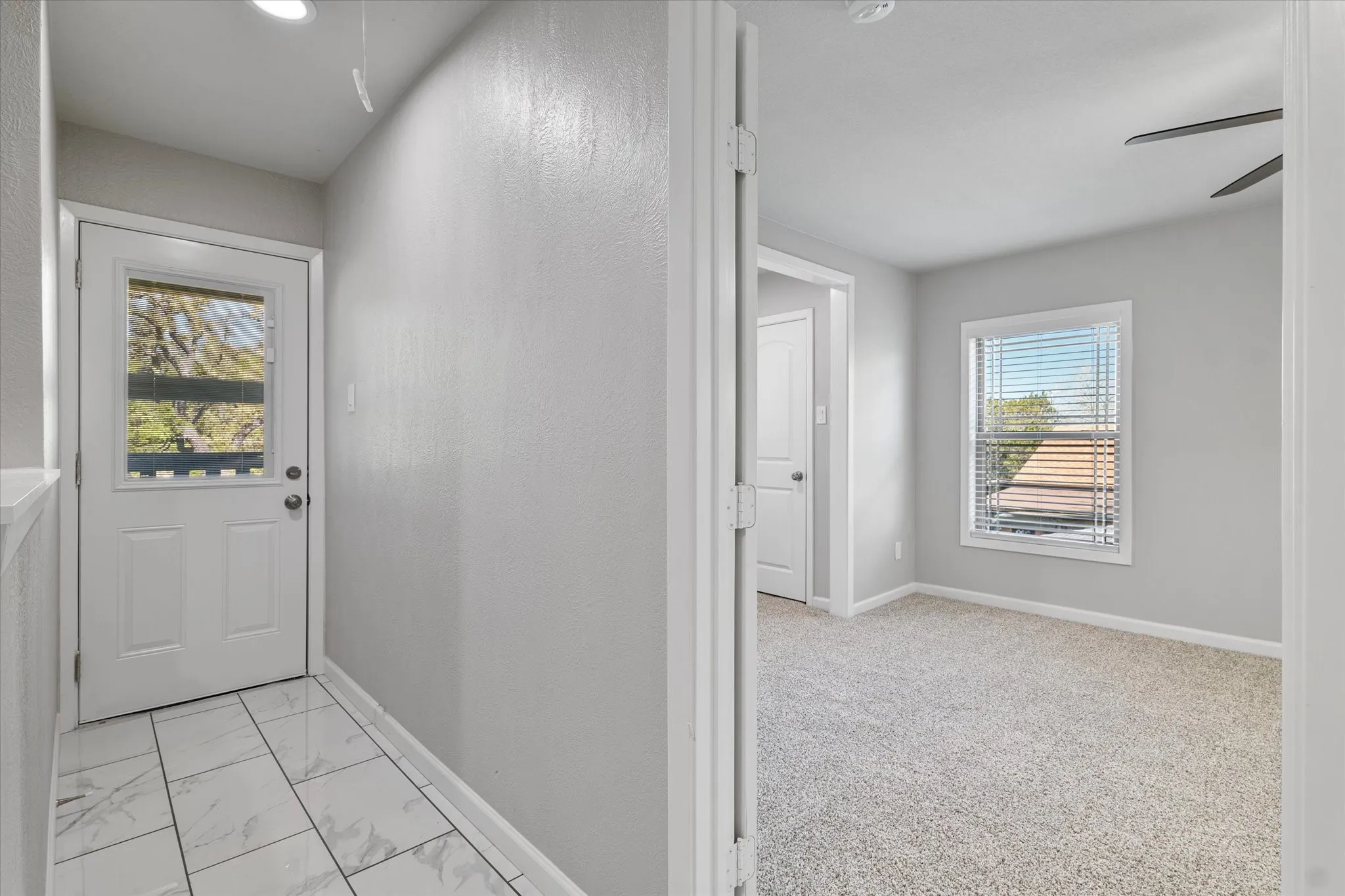Entryway featuring ceiling fan and marble finish flooring