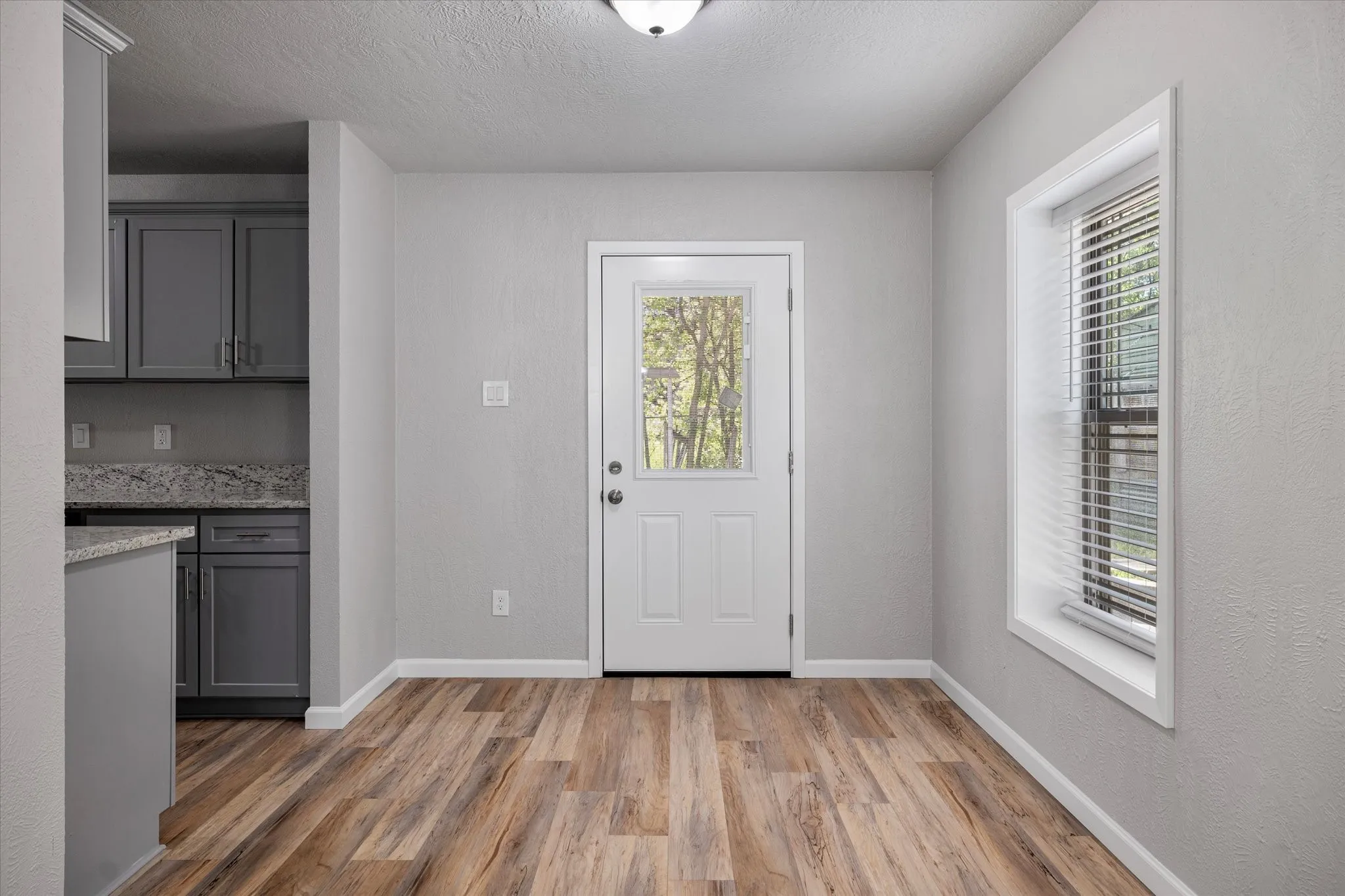 Doorway featuring healthy amount of natural light, wood finished floors, and a textured ceiling