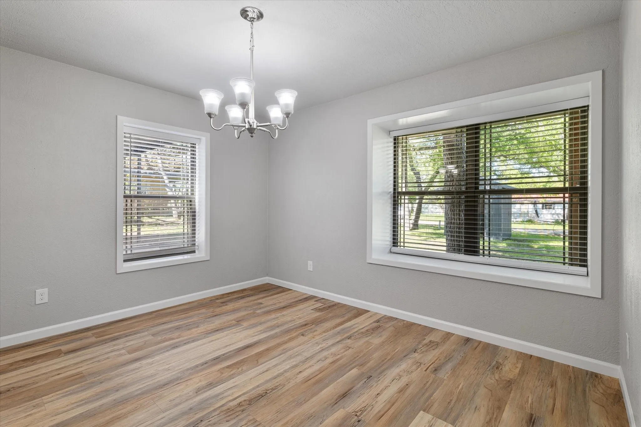 Unfurnished room featuring a chandelier and light wood-type flooring