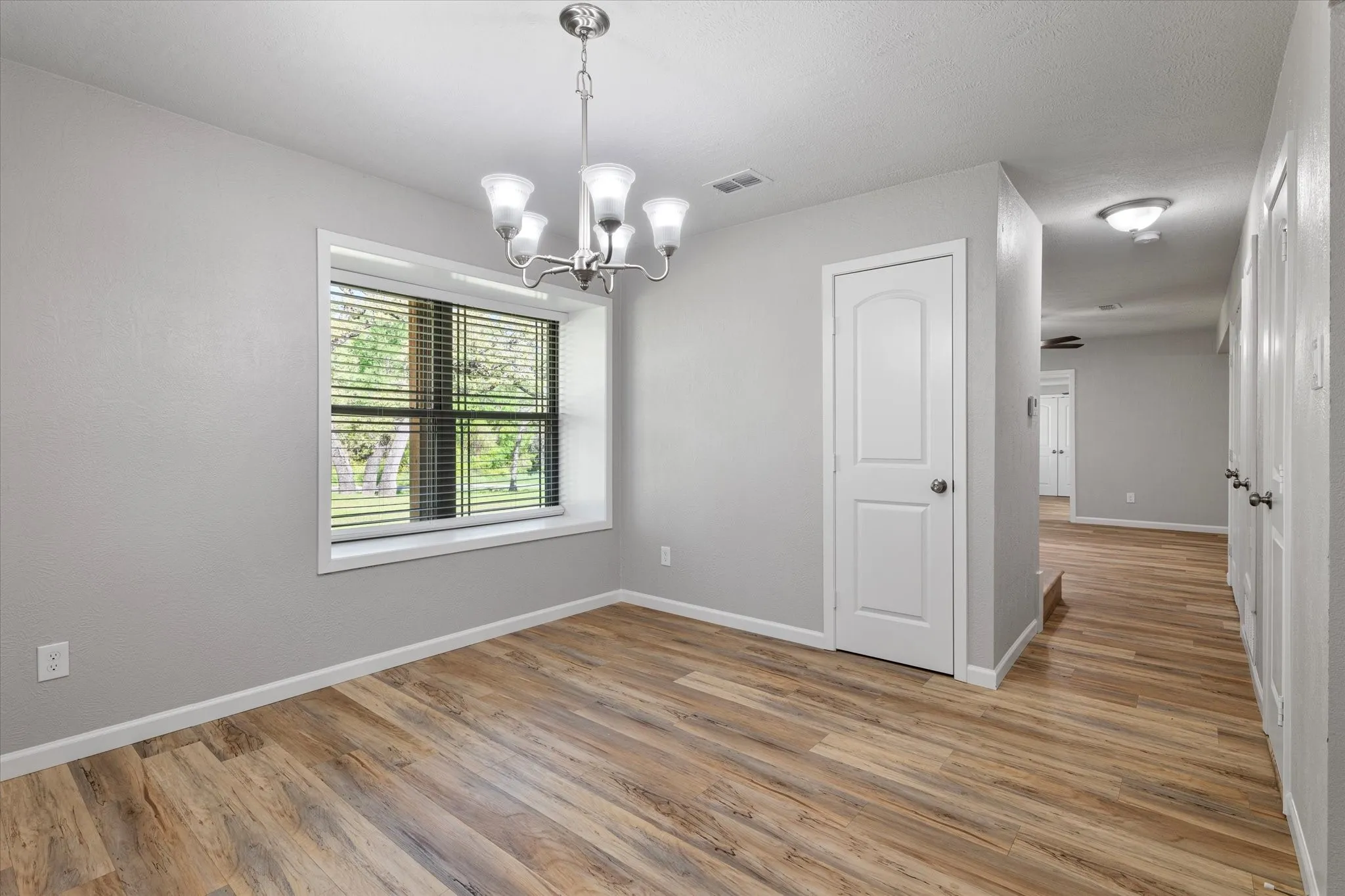 Unfurnished dining area with hanging lights and light wood-style flooring
