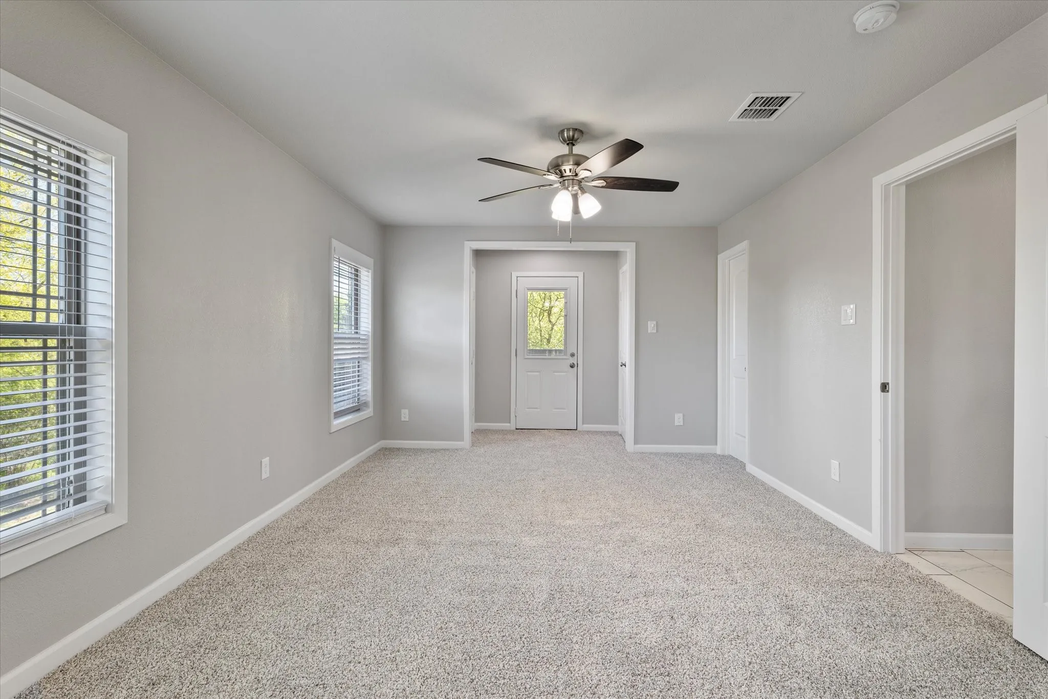 Unfurnished room with a ceiling fan and light colored carpet
