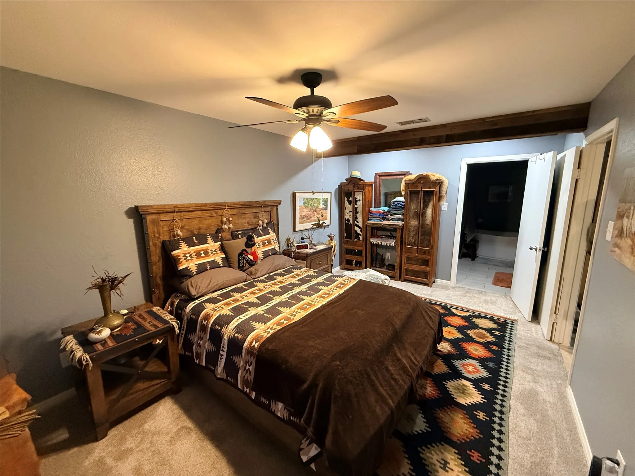 Bedroom with light colored carpet, a ceiling fan, and ensuite bath