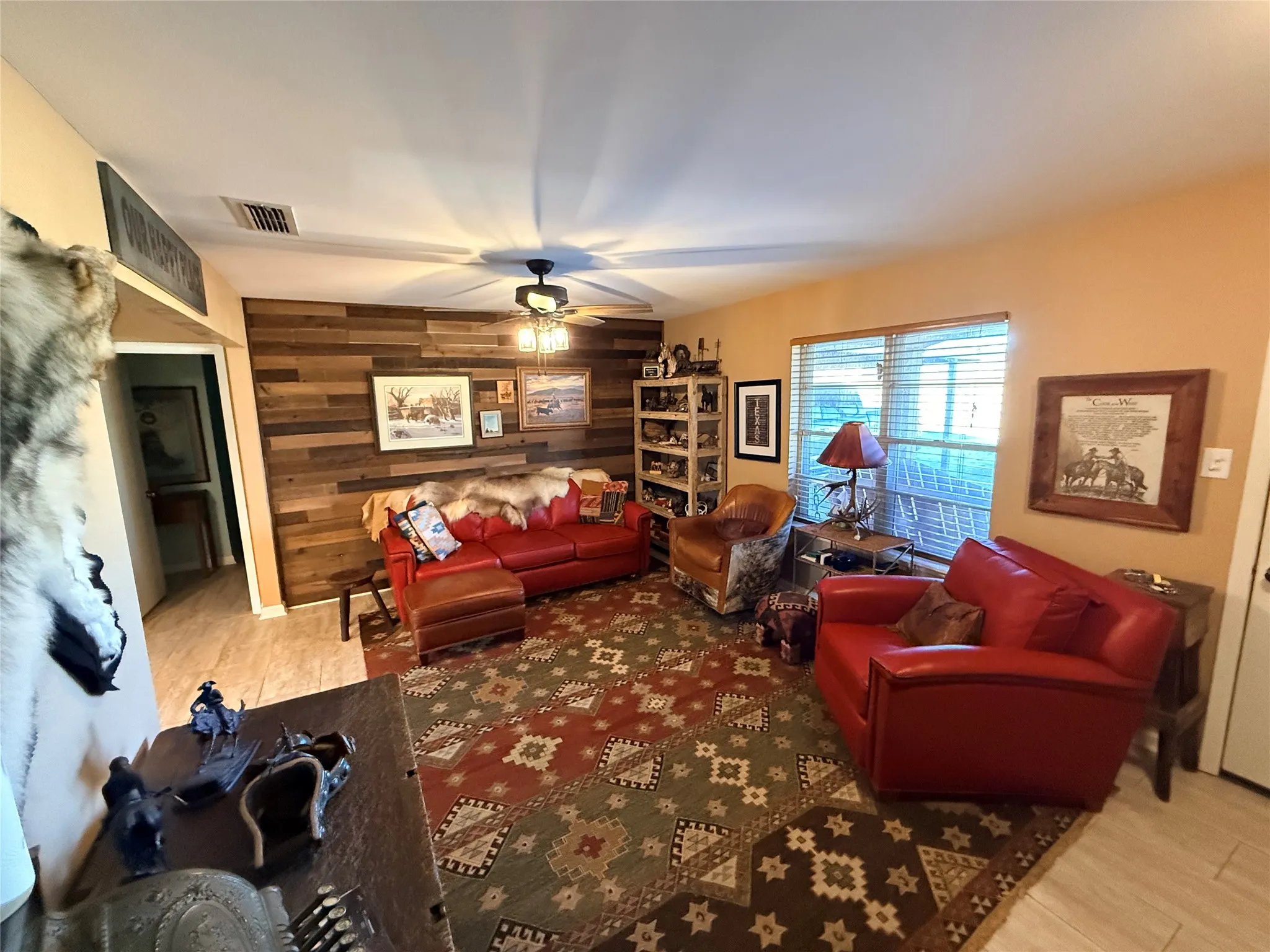 Living room featuring wooden walls, ceiling fan, and light wood-style flooring