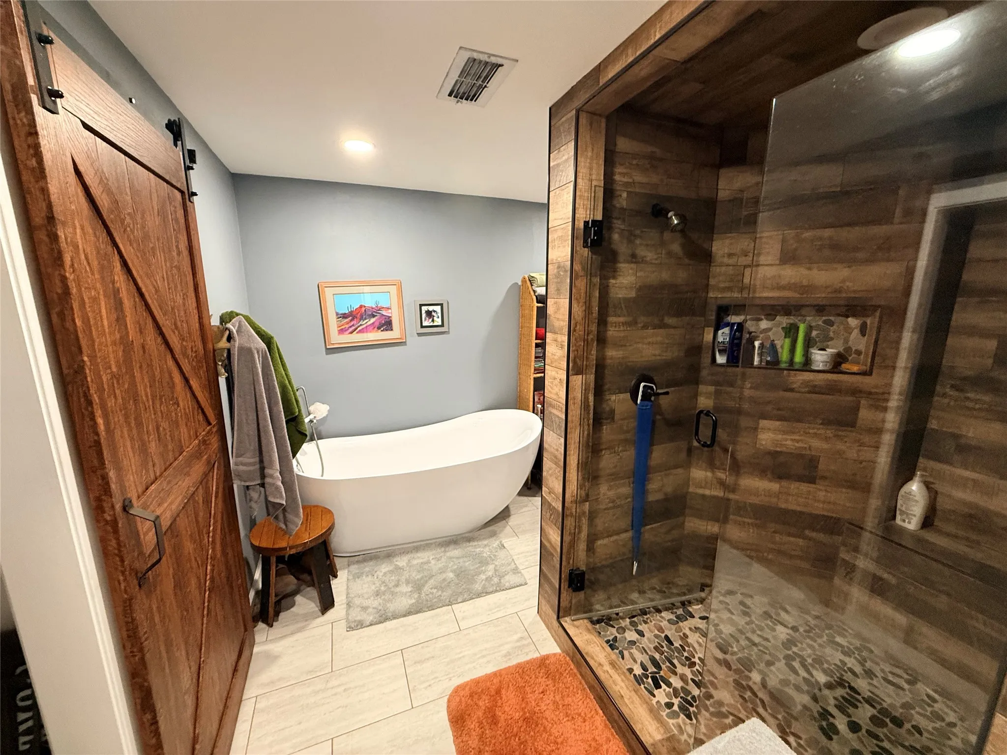 Bathroom with a soaking tub, a shower stall, and light tile patterned flooring