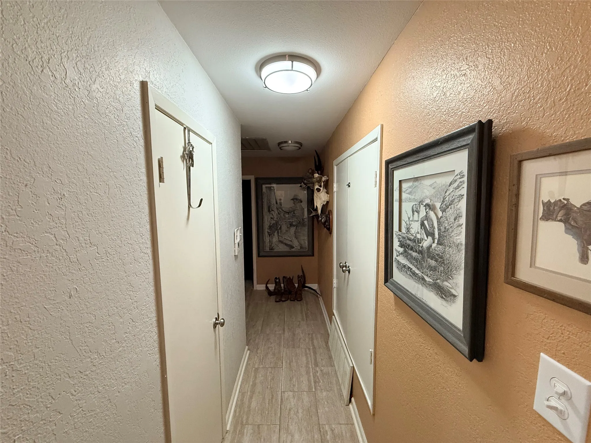 Hall featuring a textured wall and baseboards