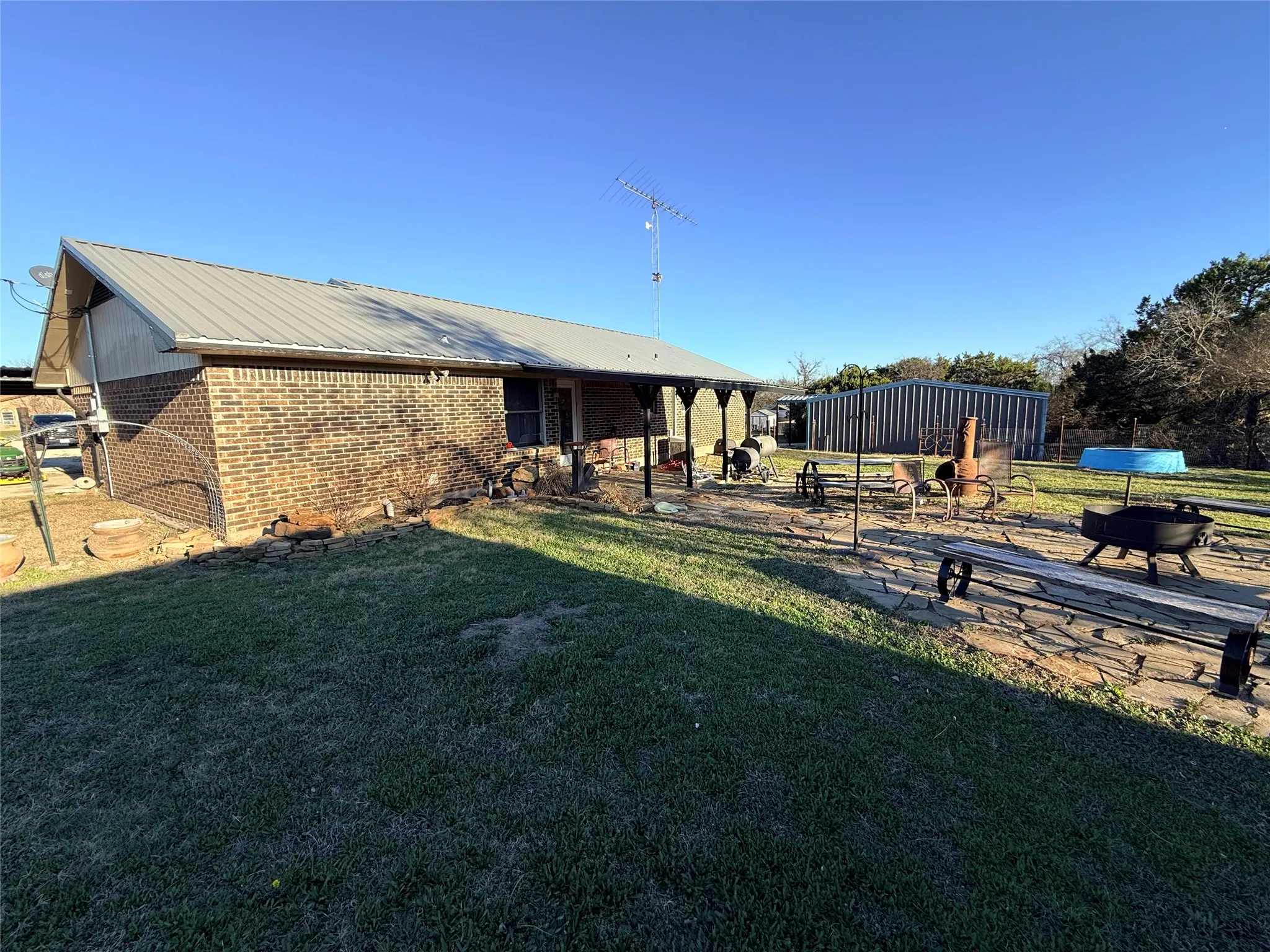 Back of property featuring a patio area, a metal roof, a yard, and brick siding