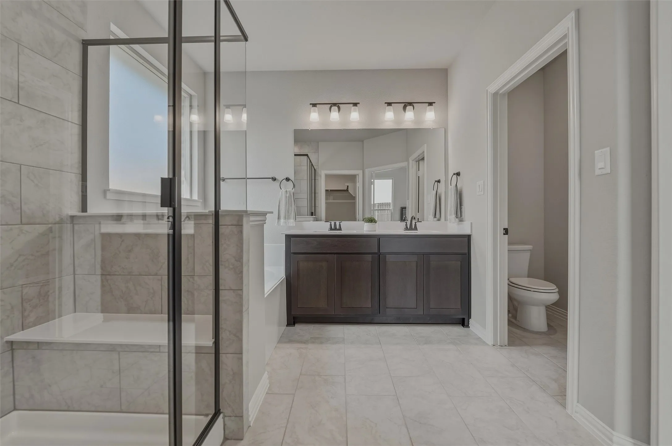 Glass-enclosed shower with tiled walls and an integrated bench