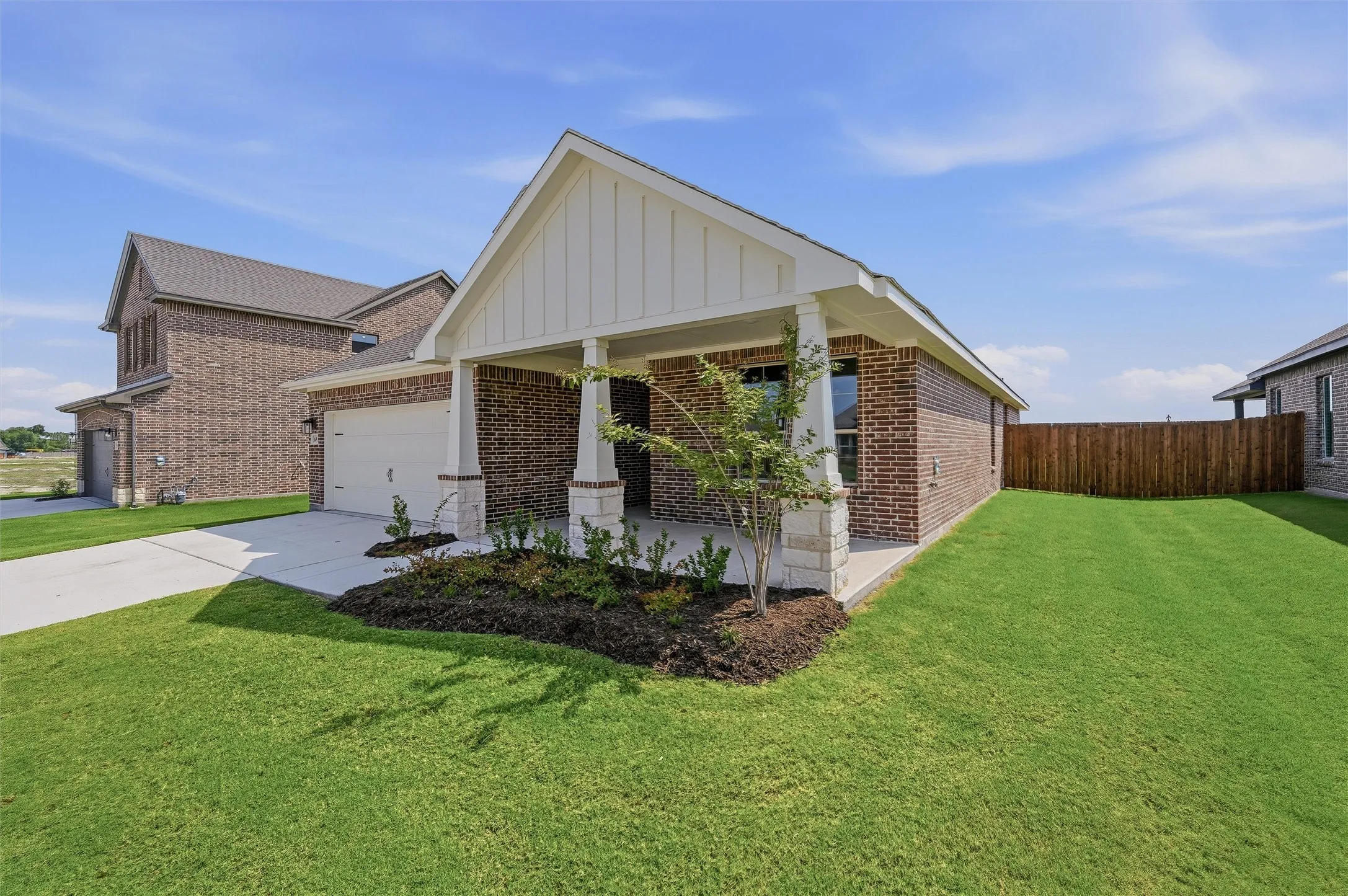 Brick exterior with stone accents, covered entry, attached garage, and a lush lawn