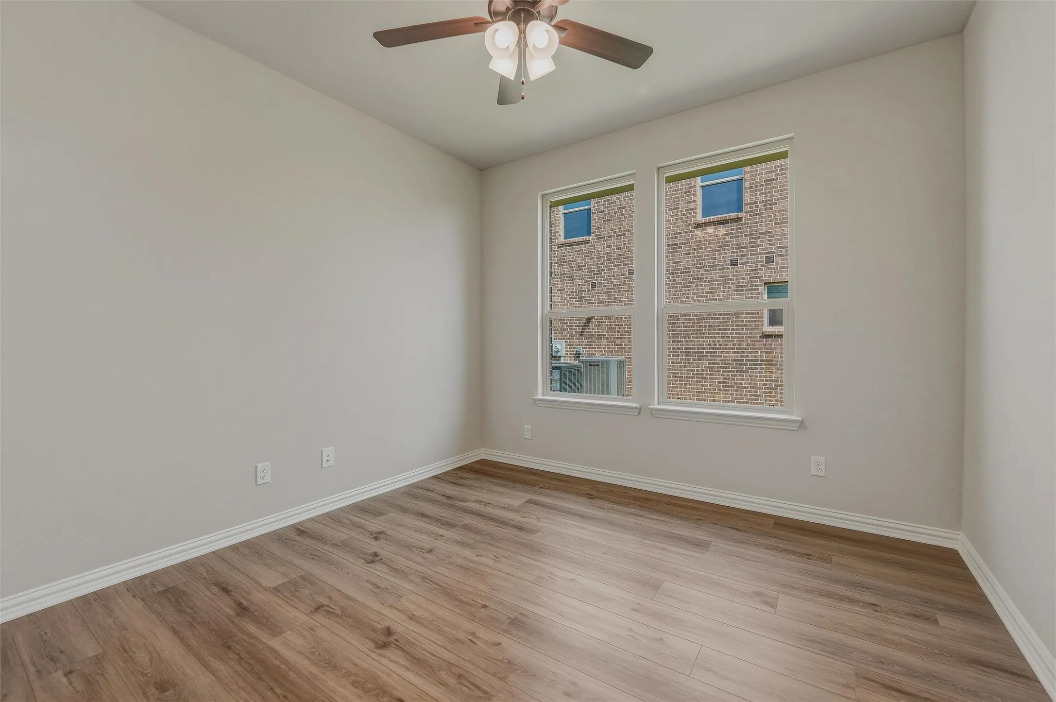 Wood-finish flooring, white trim, recessed windows, ceiling fan with integrated lighting