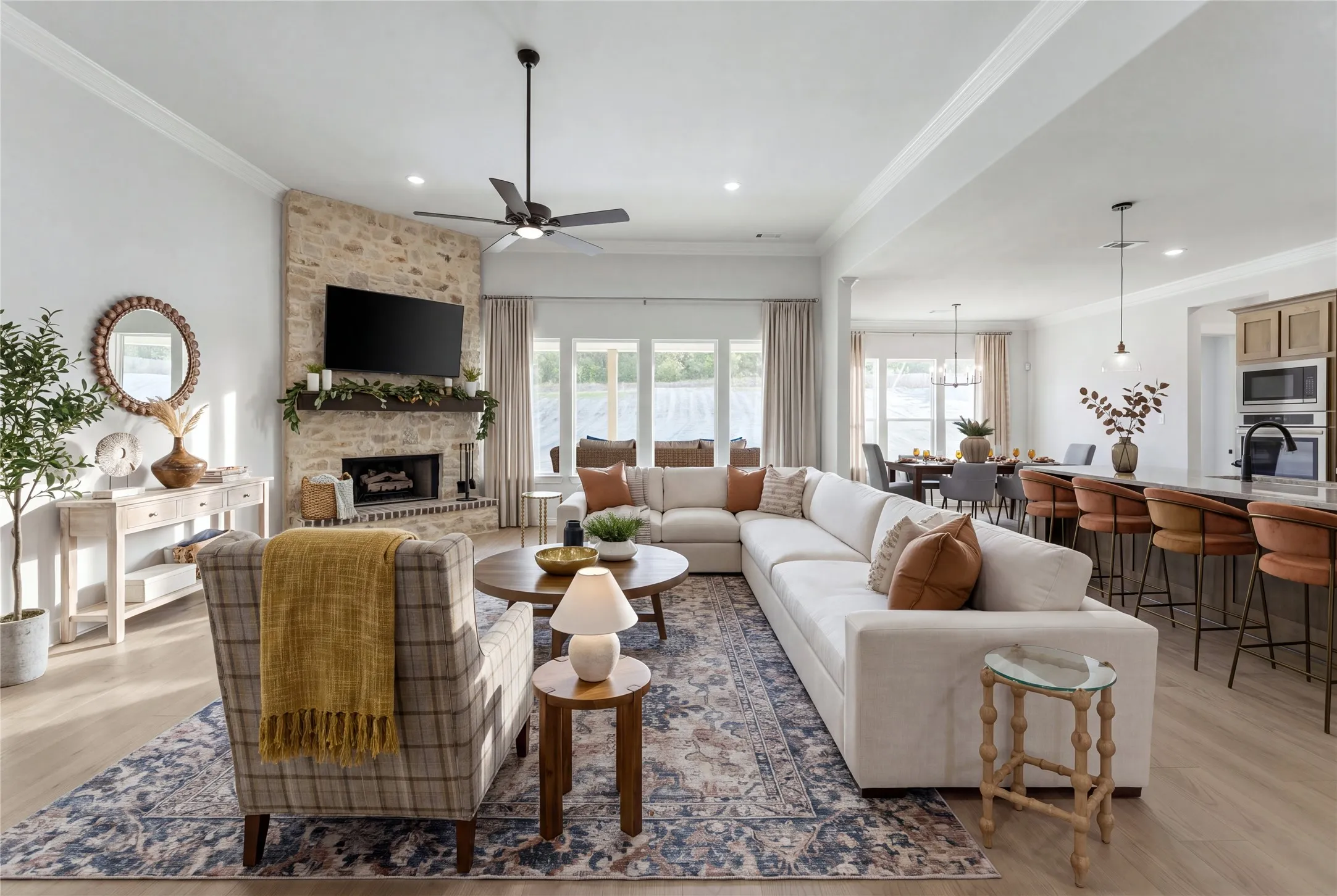 Open-concept living area with a stone-clad fireplace and wood-finish flooring