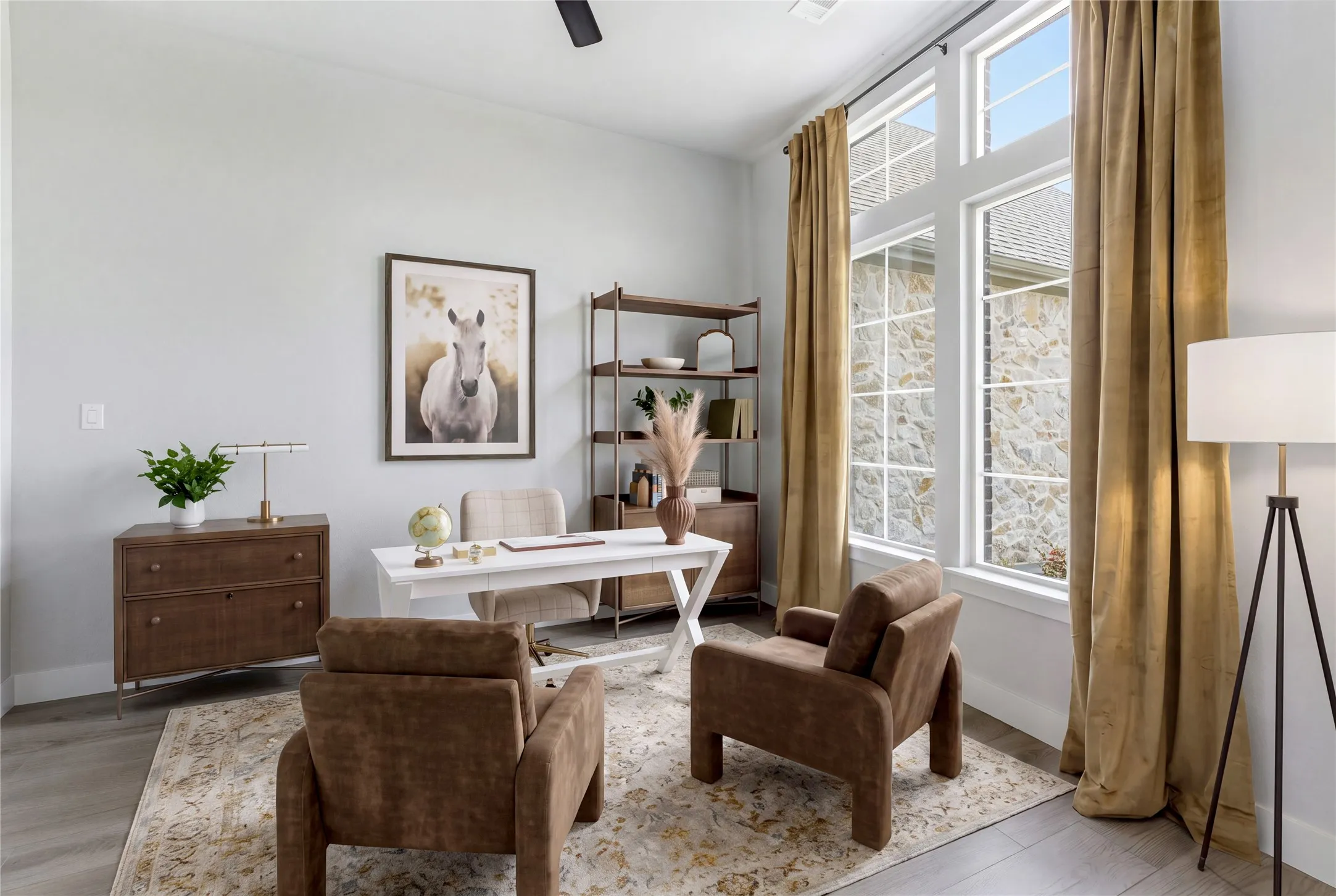 Expansive room with high ceilings, large windows, wood-finish flooring, and stone exterior visible through windows