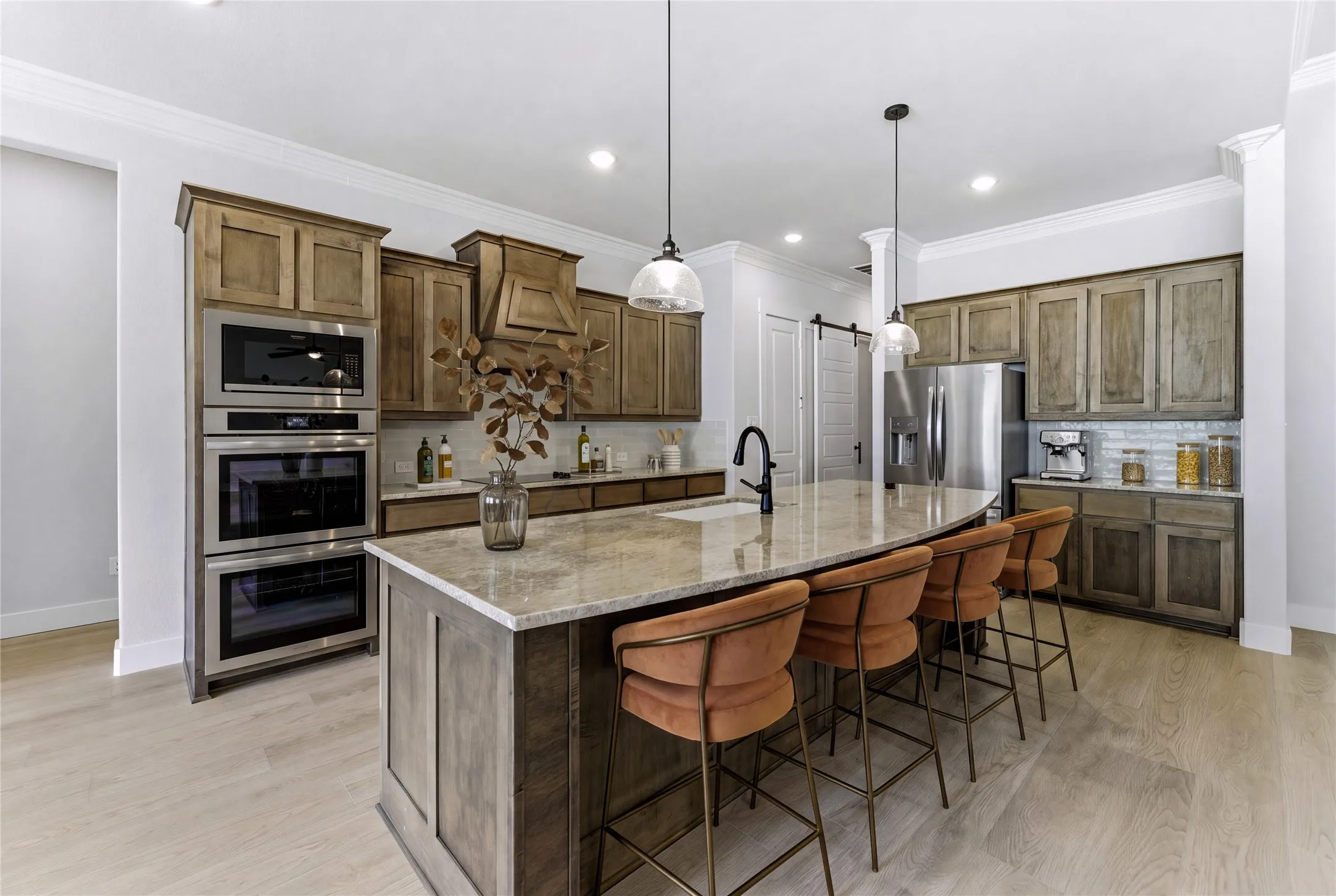 Gourmet kitchen with wood-finish cabinetry, built-in stainless steel appliances, and an expansive island with a stone countertop