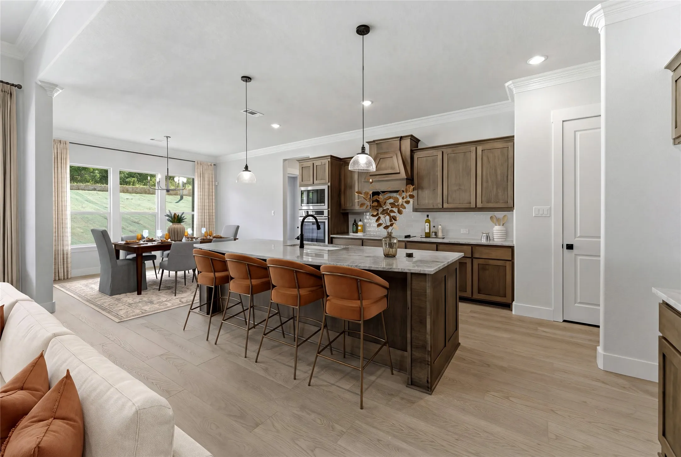 Open-concept kitchen and dining area featuring wood-finish flooring, a large island with seating, dark wood cabinetry, and stainless steel appliances