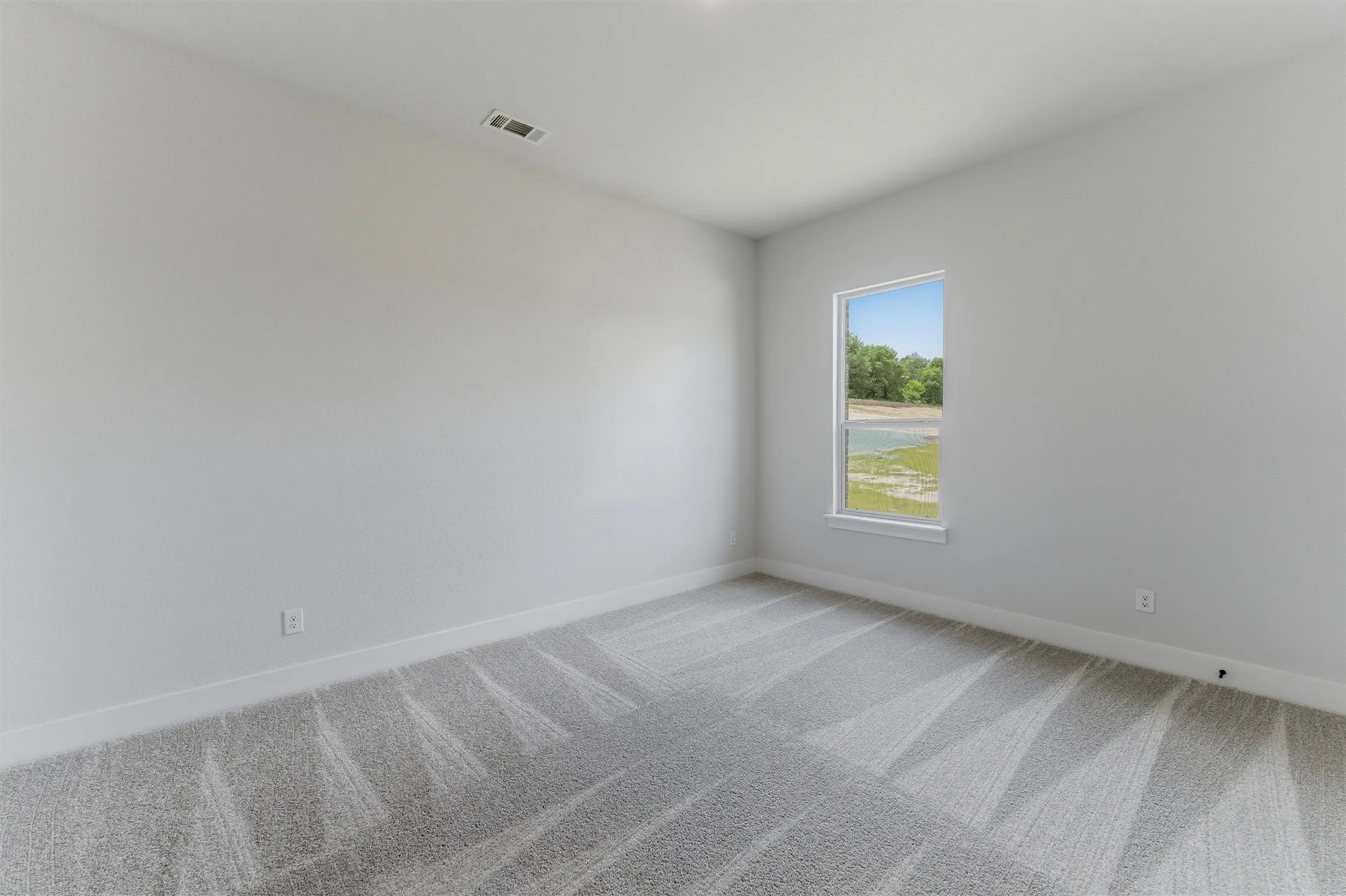 Bright interior space featuring light gray walls, white trim, and patterned gray carpeting
