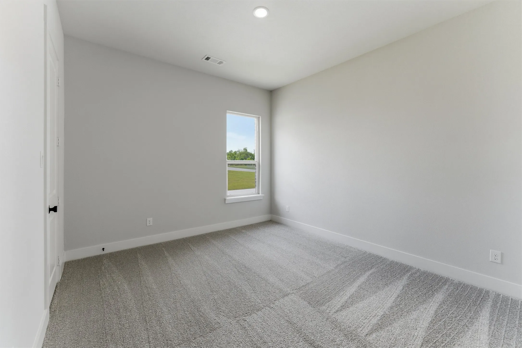 Neutral-toned room featuring a single window and recessed lighting