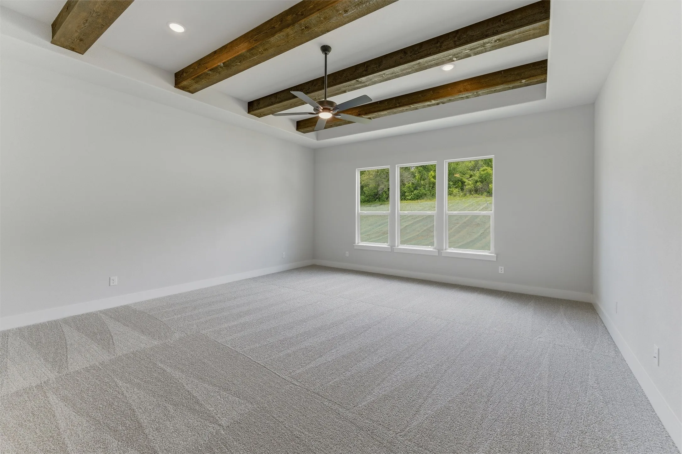 Tray ceiling with exposed wood beams, recessed lighting, and a ceiling fan